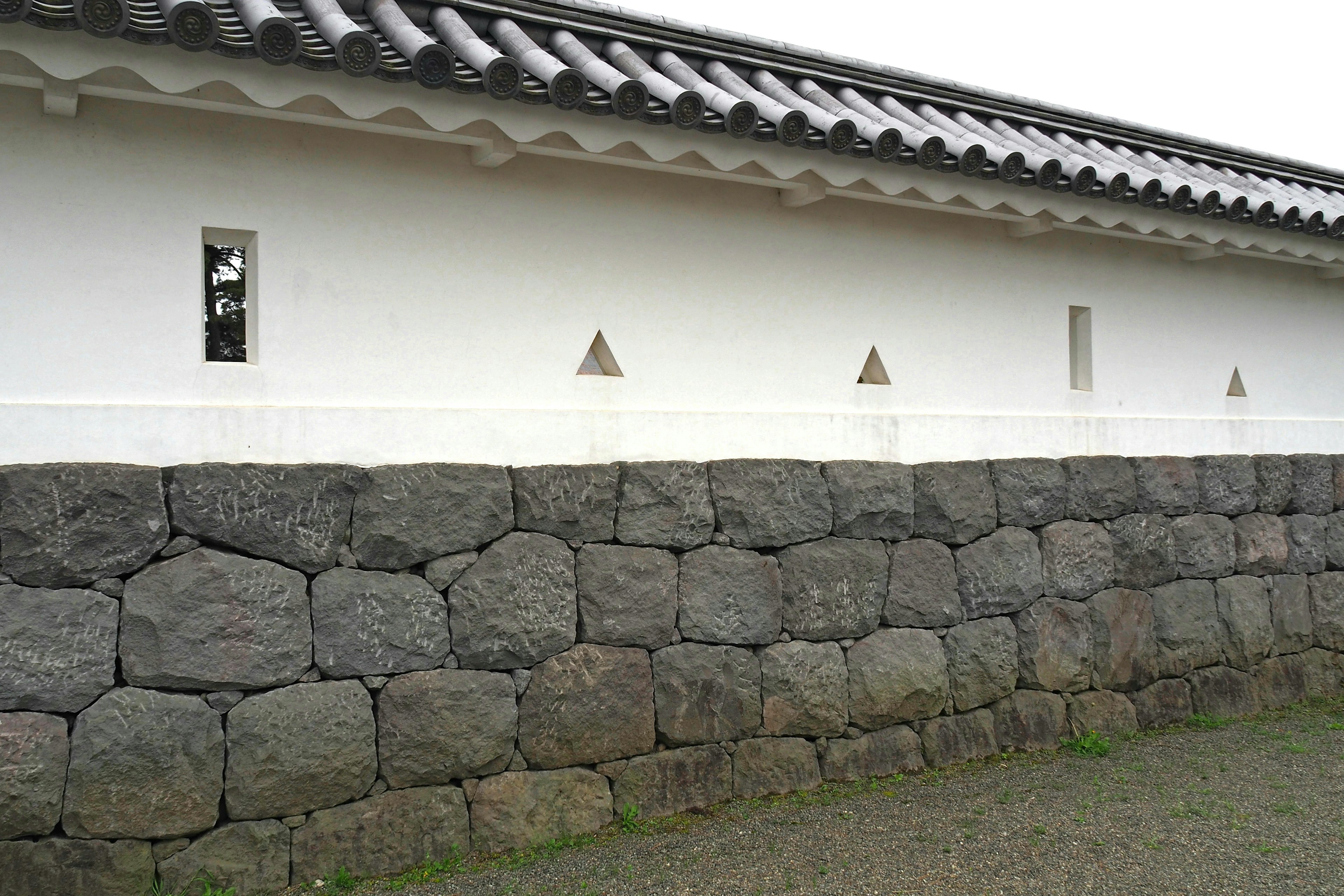 Traditional Japanese building featuring a white wall and stone foundation