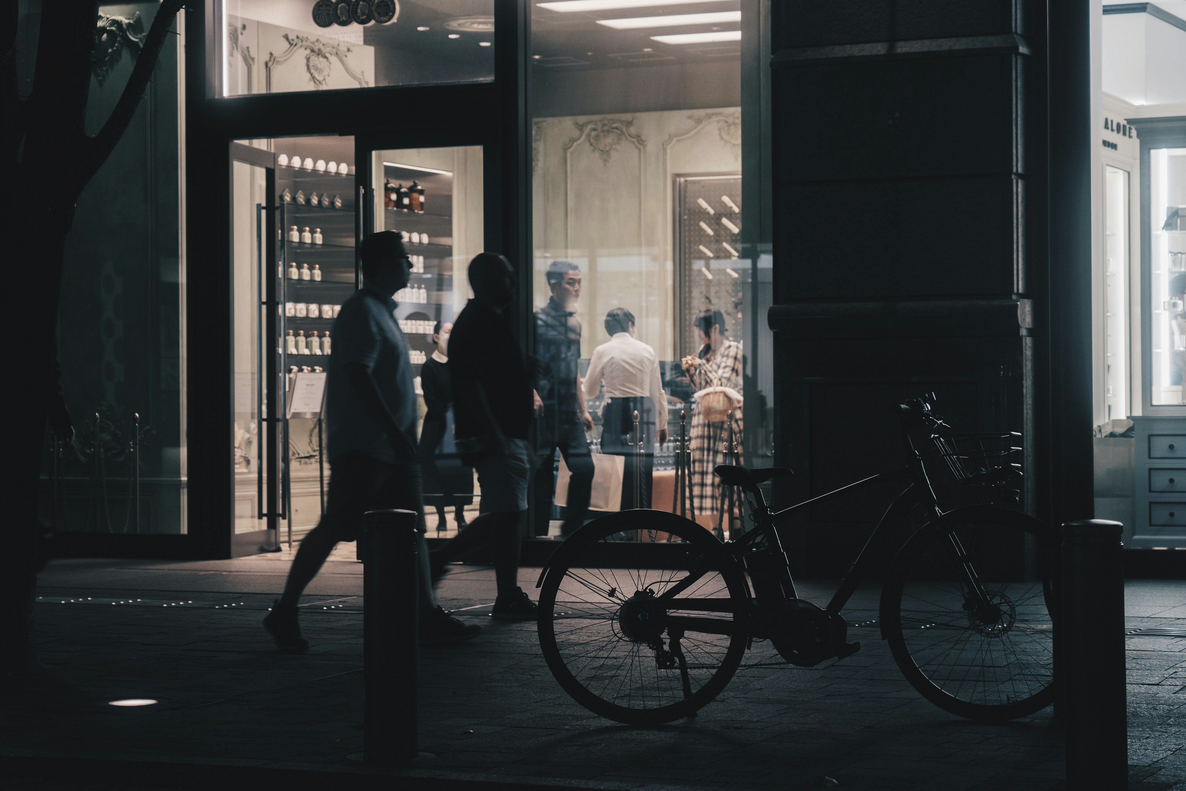 夜の街で歩く人々と自転車のシルエットが印象的な風景