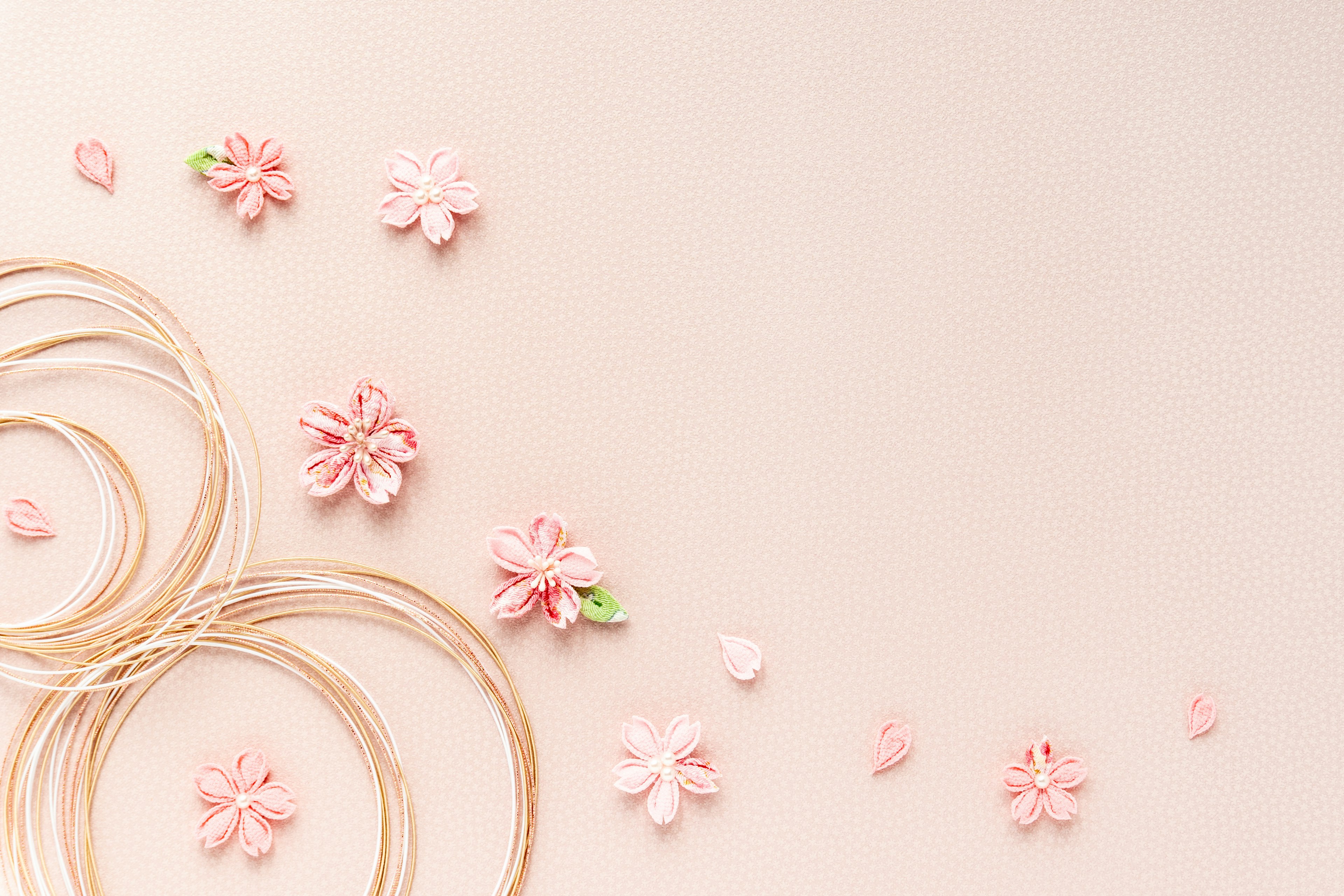 Delicate pink background with scattered flowers and string