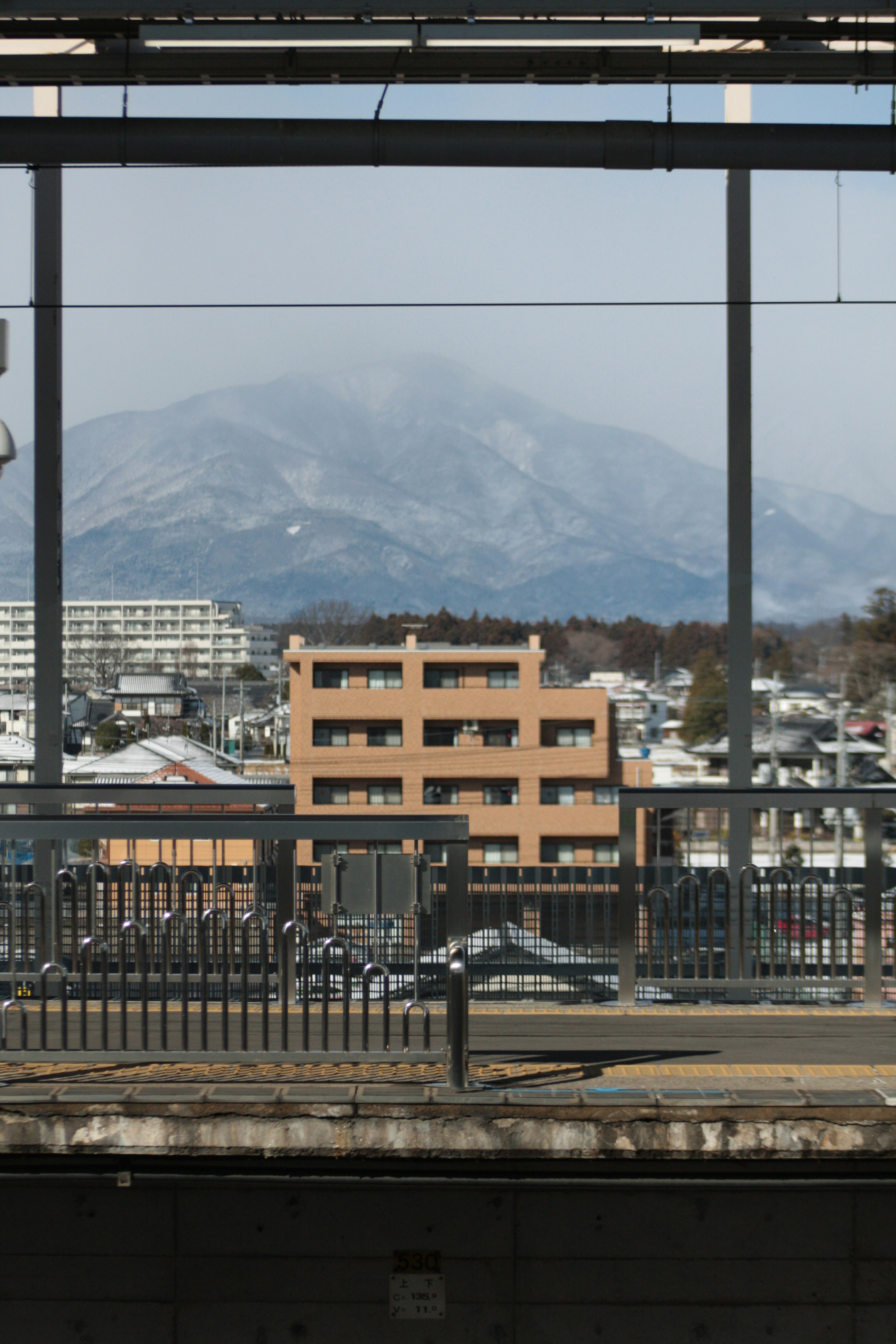 Vue d'une montagne enneigée et de bâtiments depuis une fenêtre de gare