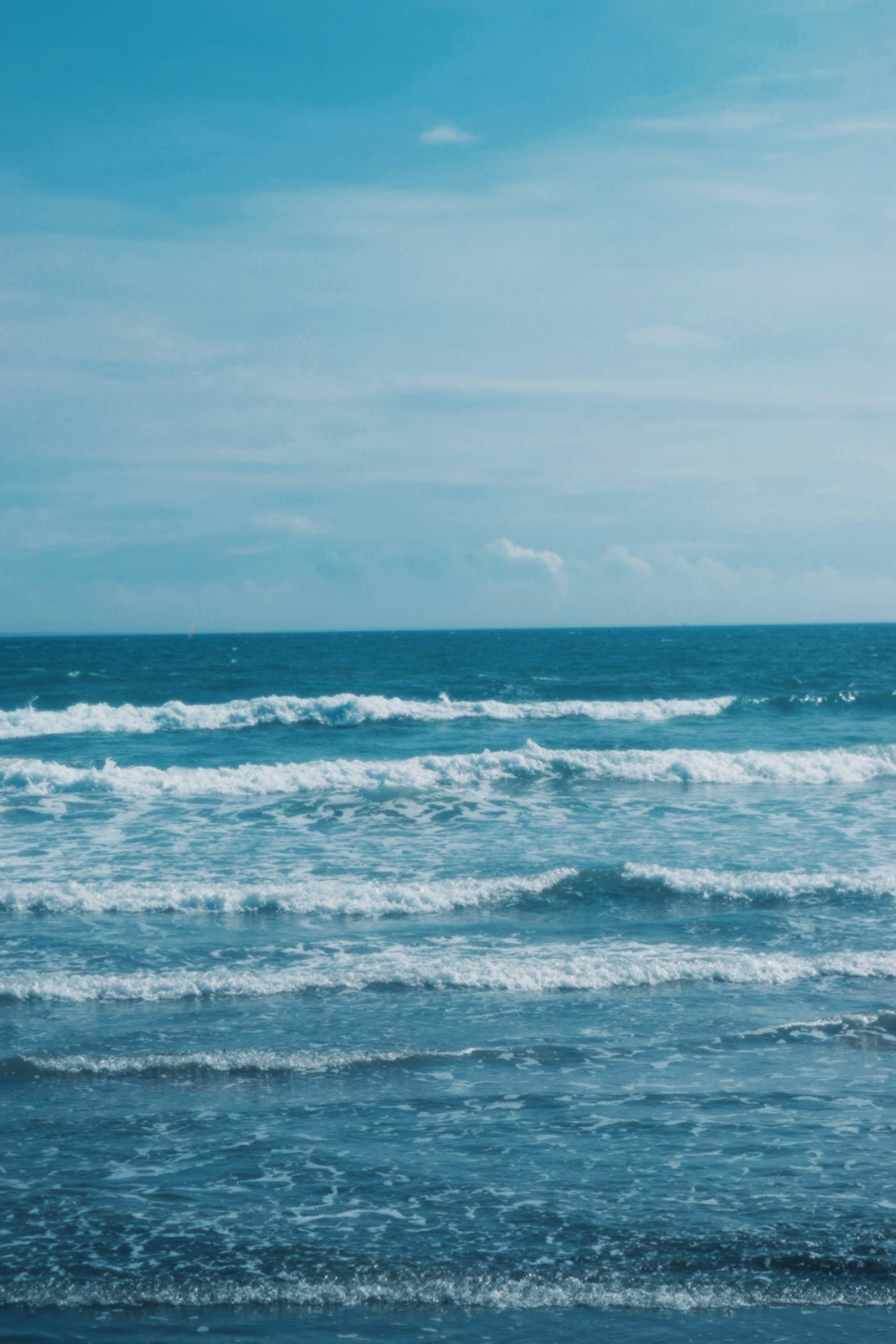 Pemandangan laut biru dengan ombak di bawah langit mendung