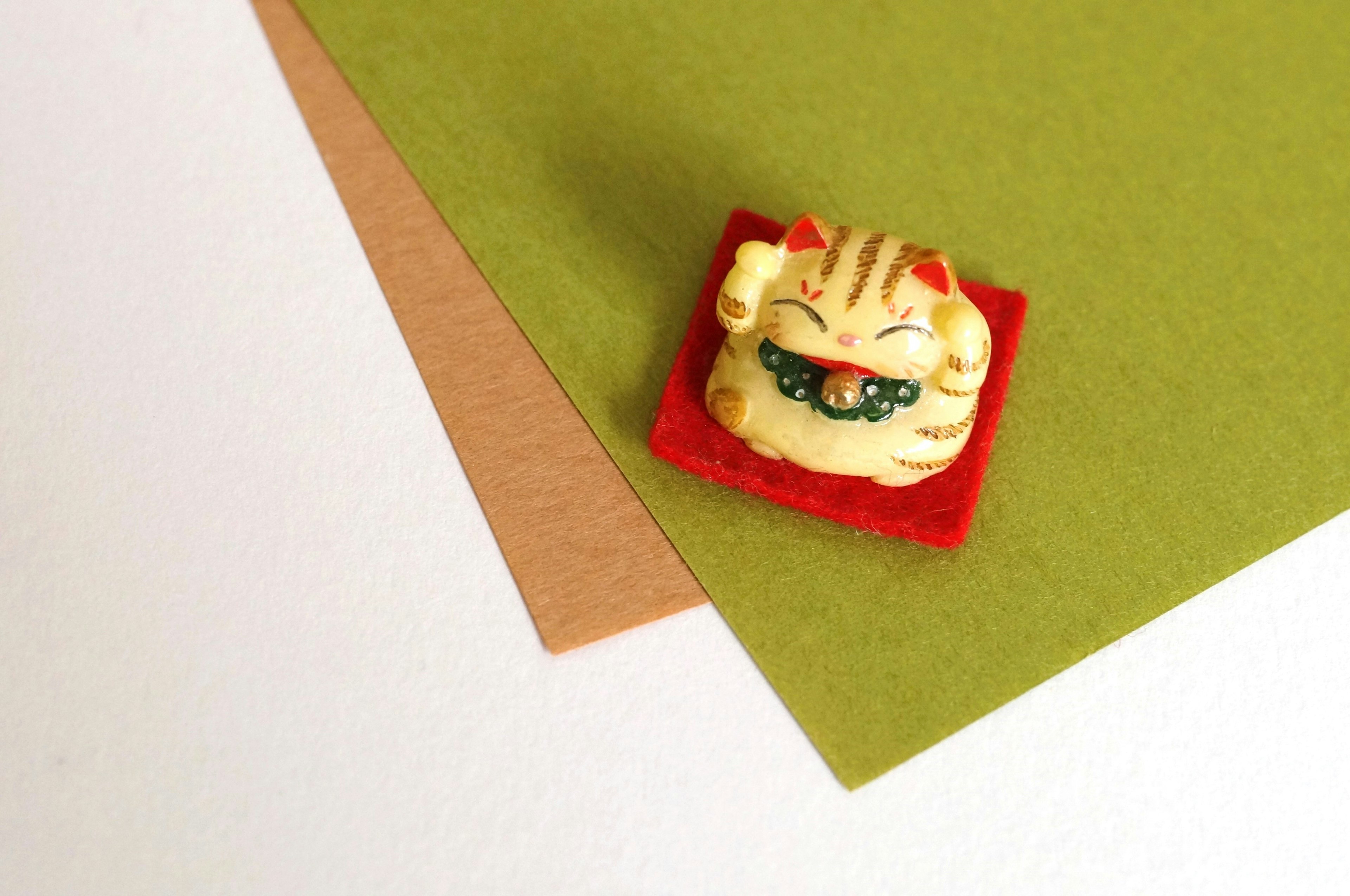 Figurine de chat posée sur du papier vert et marron