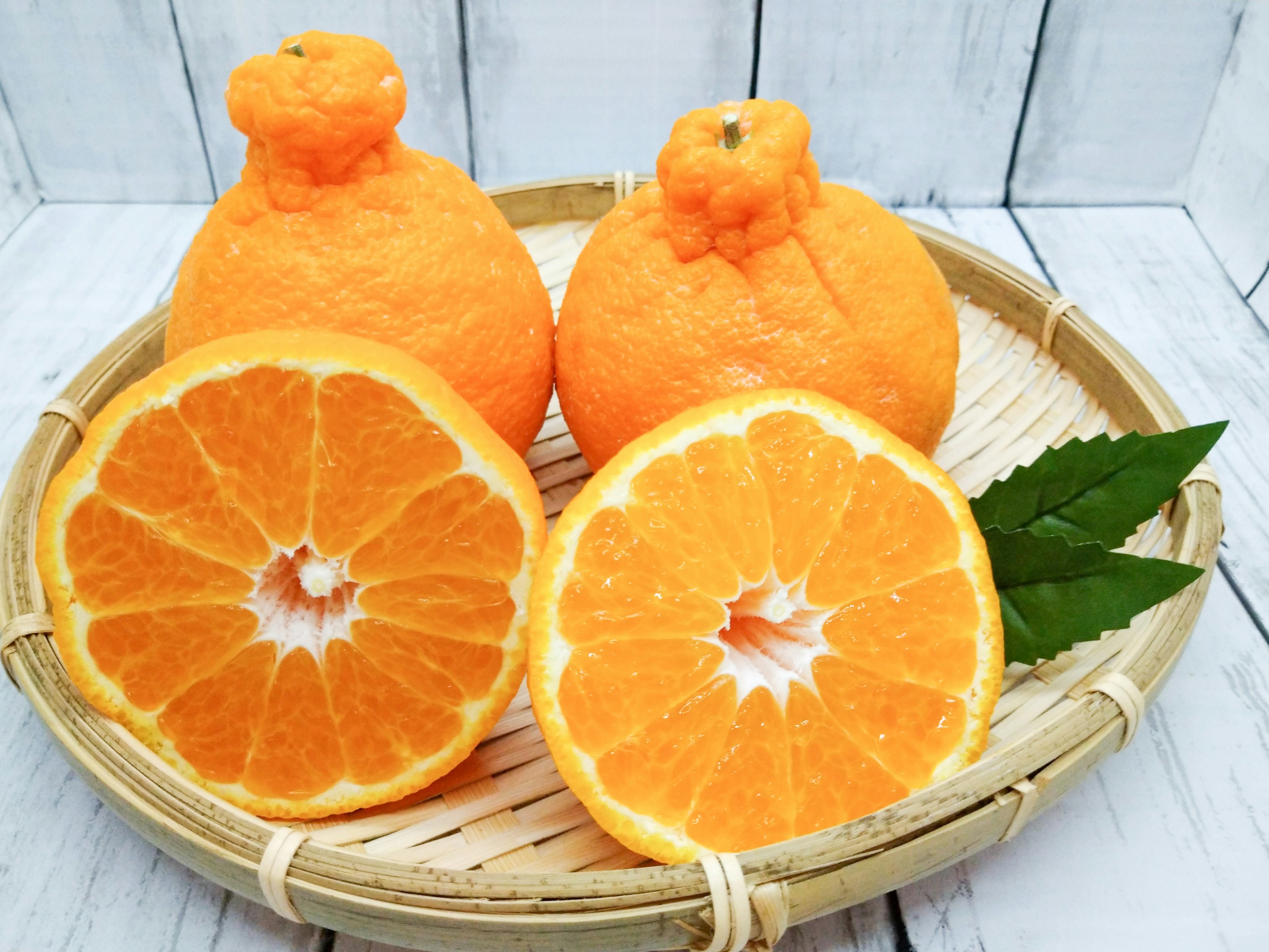 Una canasta con naranjas enteras y una naranja en rodajas mostrando el interior vibrante