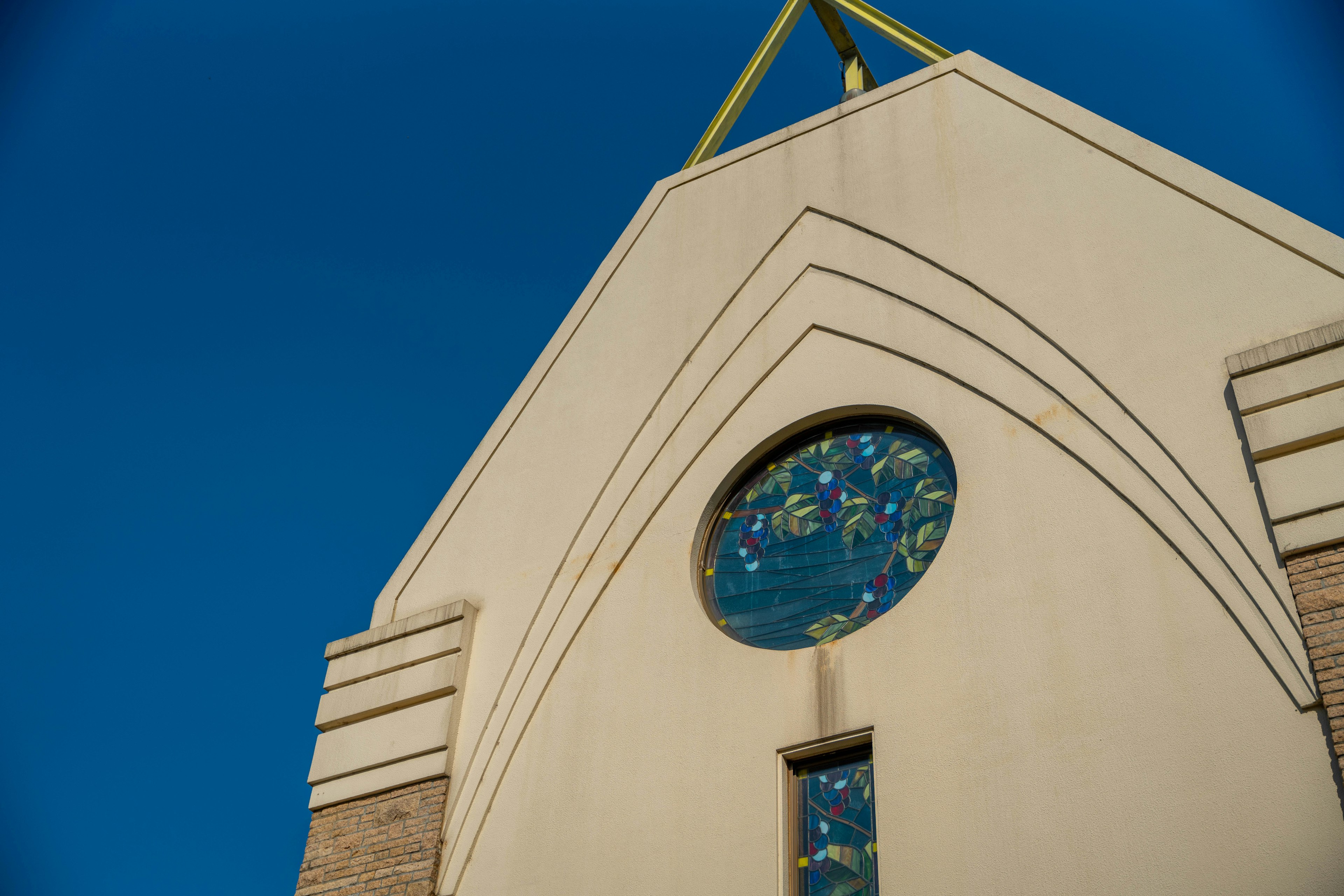 Außenansicht einer Kirche unter blauem Himmel mit Bogen-Design und buntem Glasfenster