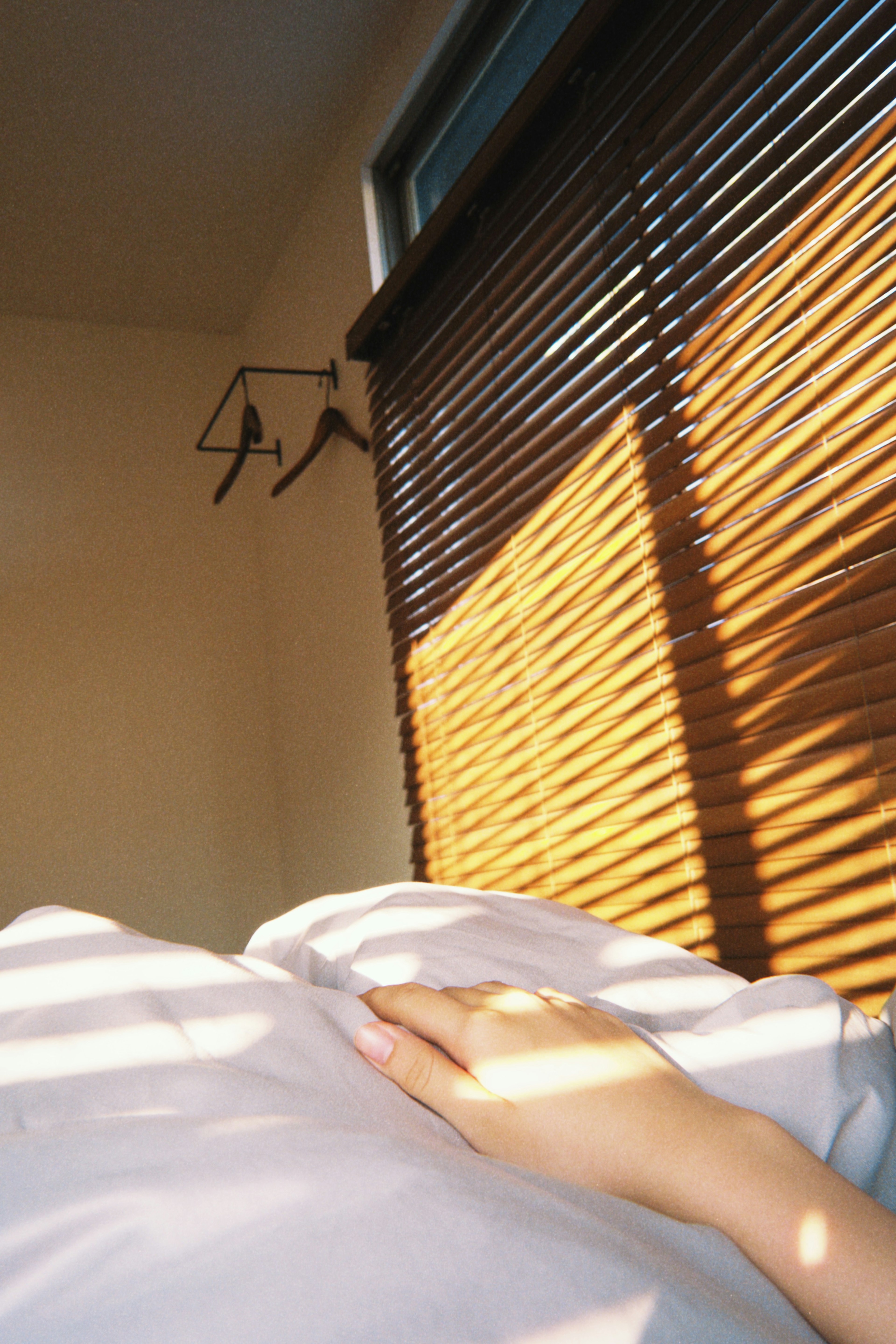 Une main reposant sur un oreiller avec de la lumière du soleil passant à travers des stores