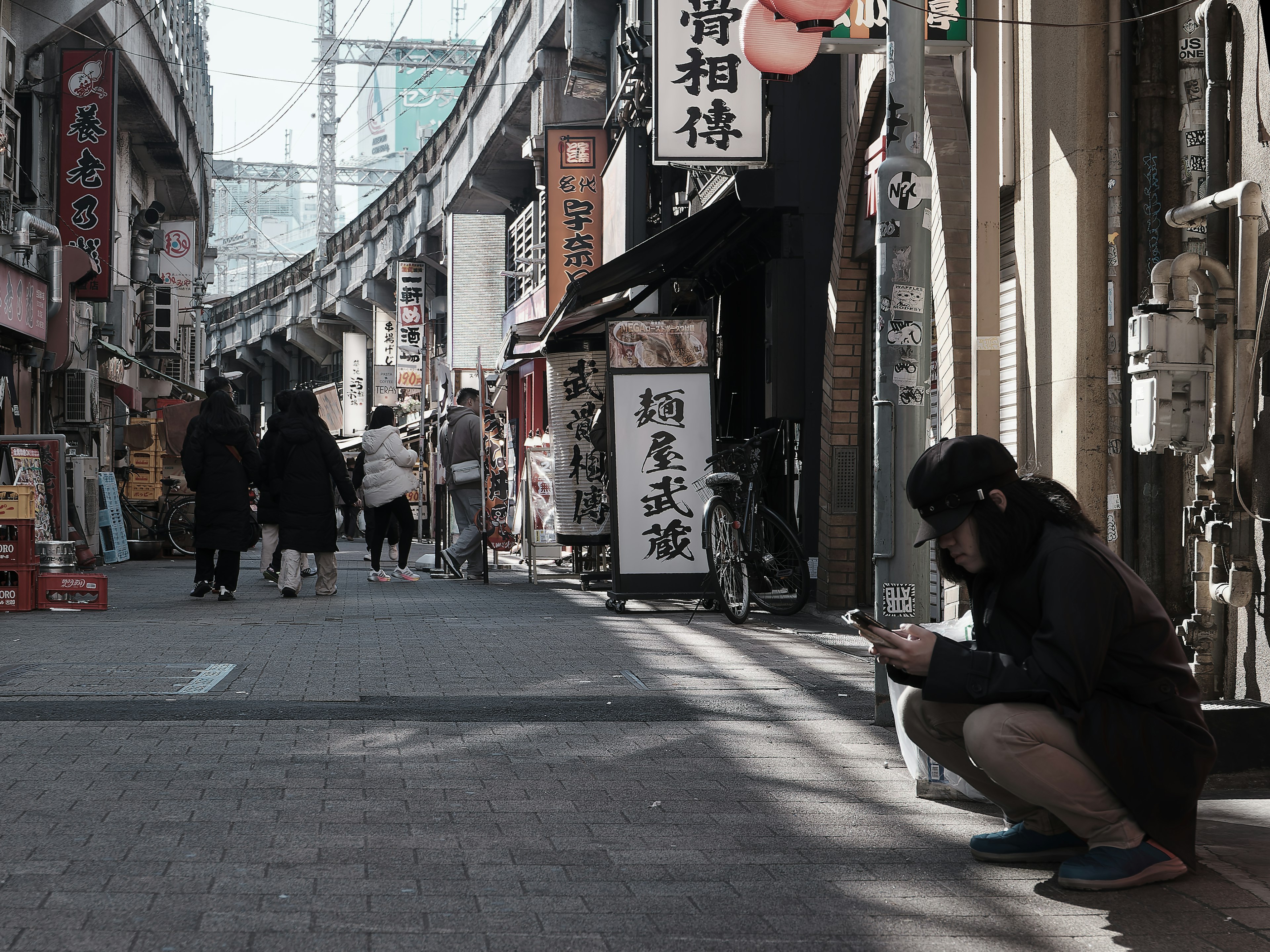 人々が行き交う通りでスマートフォンを使う女性の姿