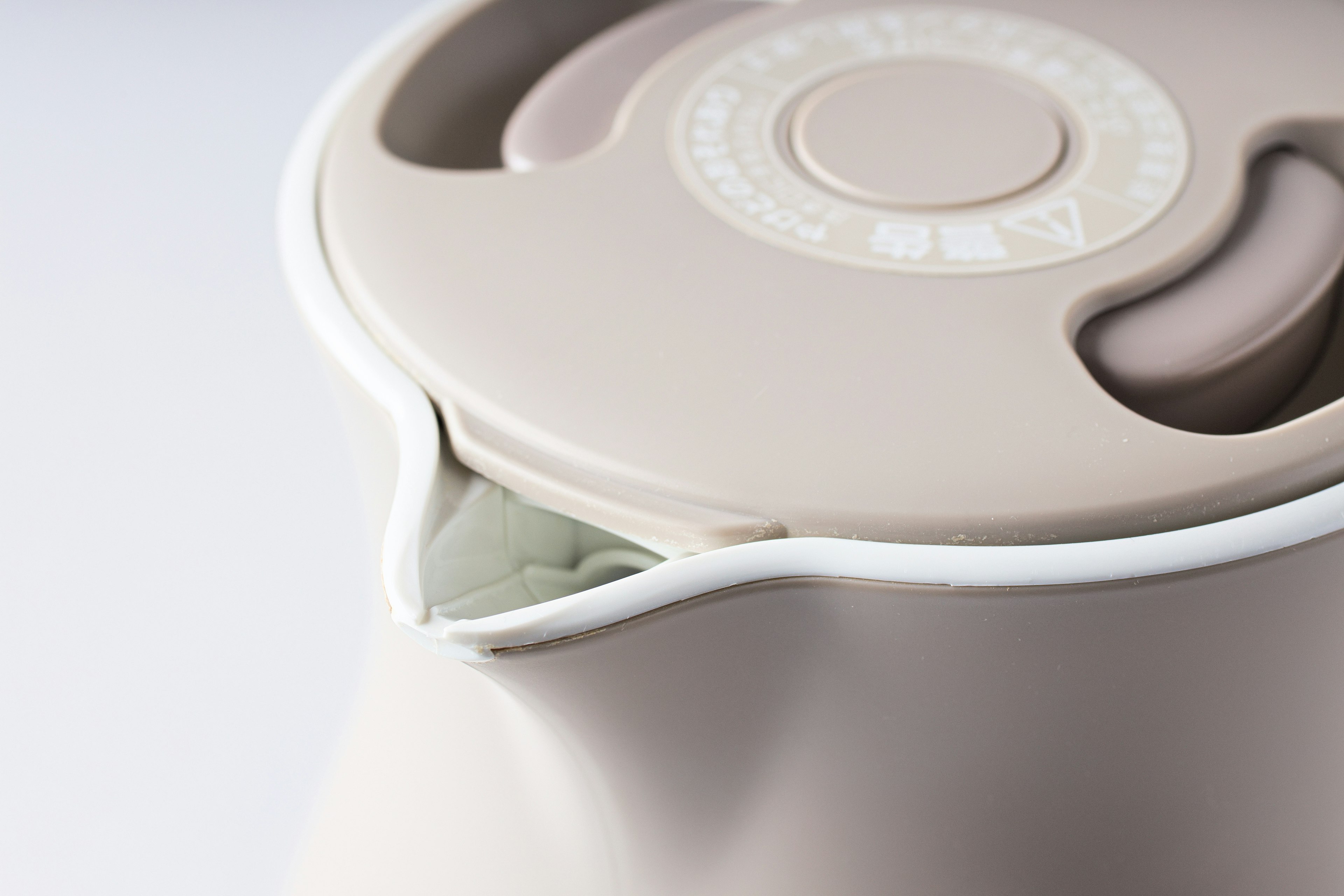 Close-up of a light-colored electric kettle lid with a spout