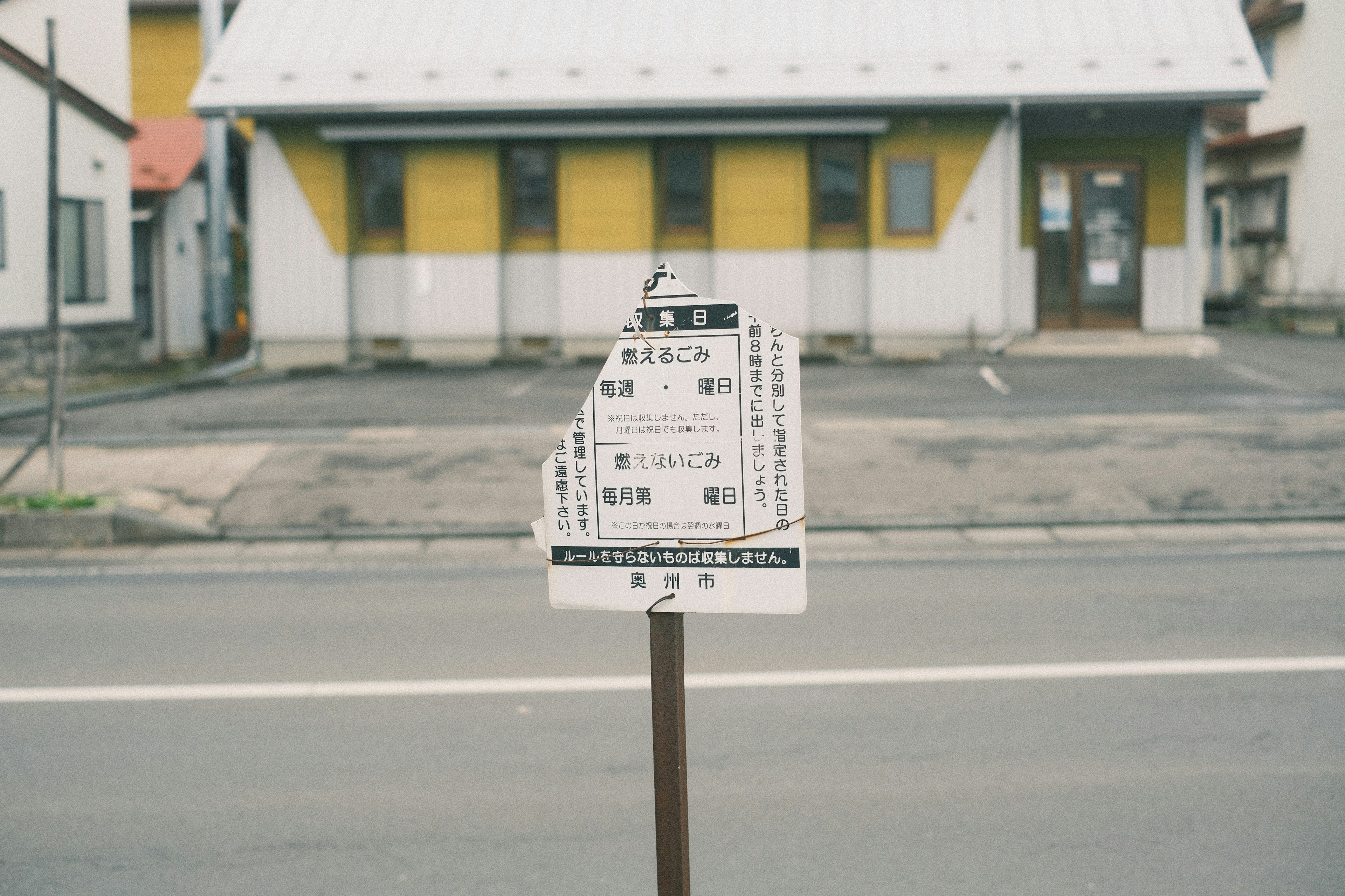 Road sign with a yellow building in the background