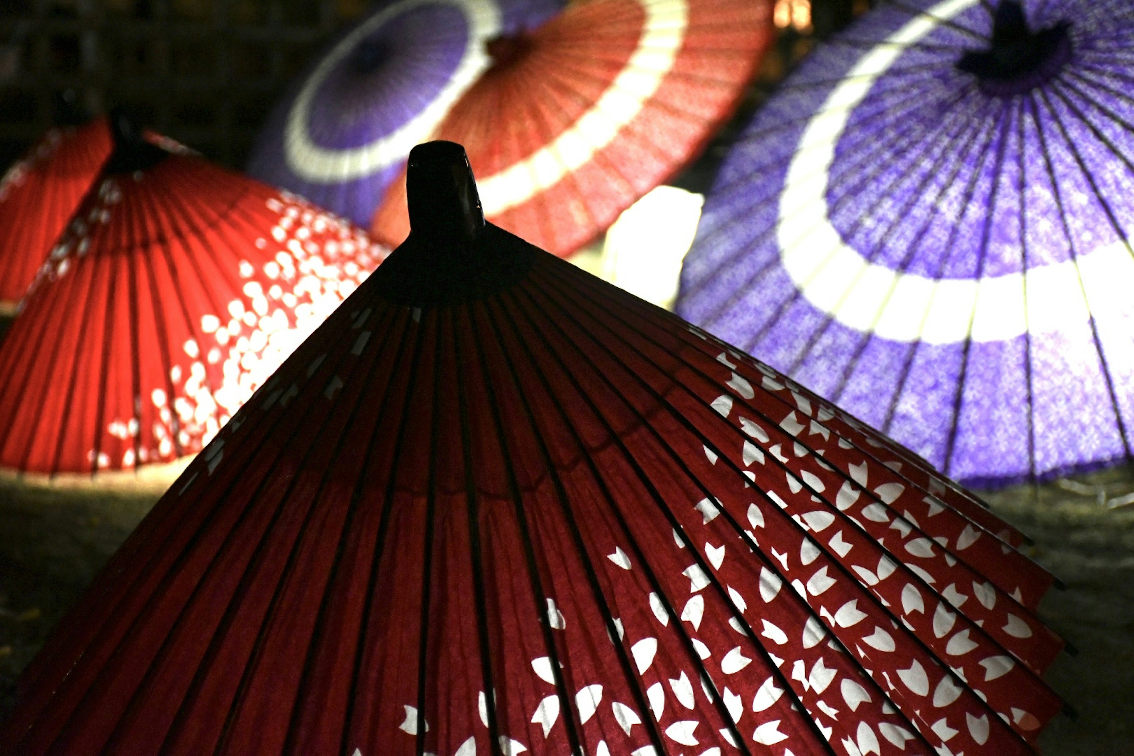 Sombrillas coloridas dispuestas en una escena nocturna sombrilla roja con patrones blancos y una sombrilla morada visible