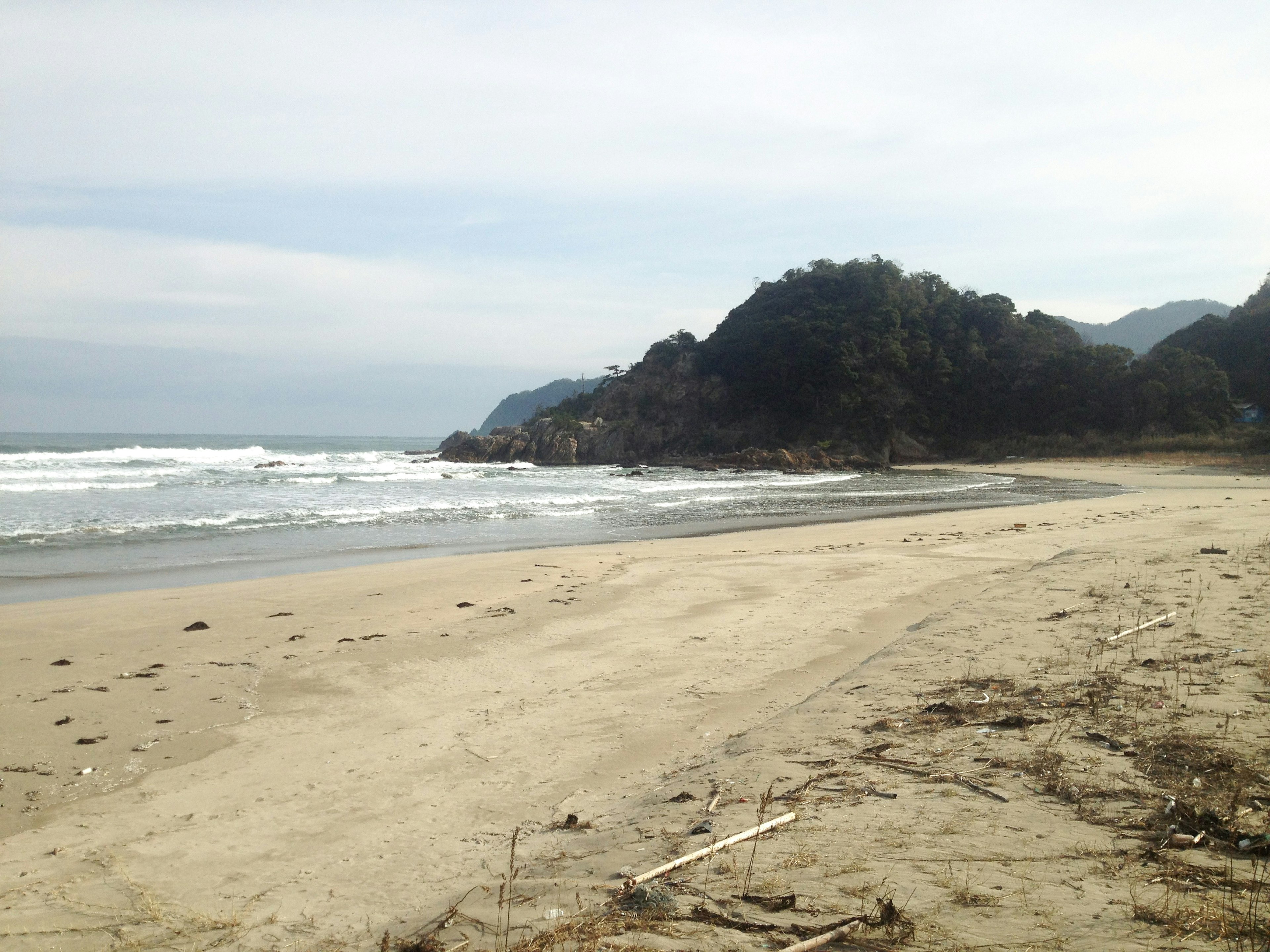 ชายหาดที่เงียบสงบพร้อมคลื่นที่นุ่มนวลและภูเขาห่างไกล