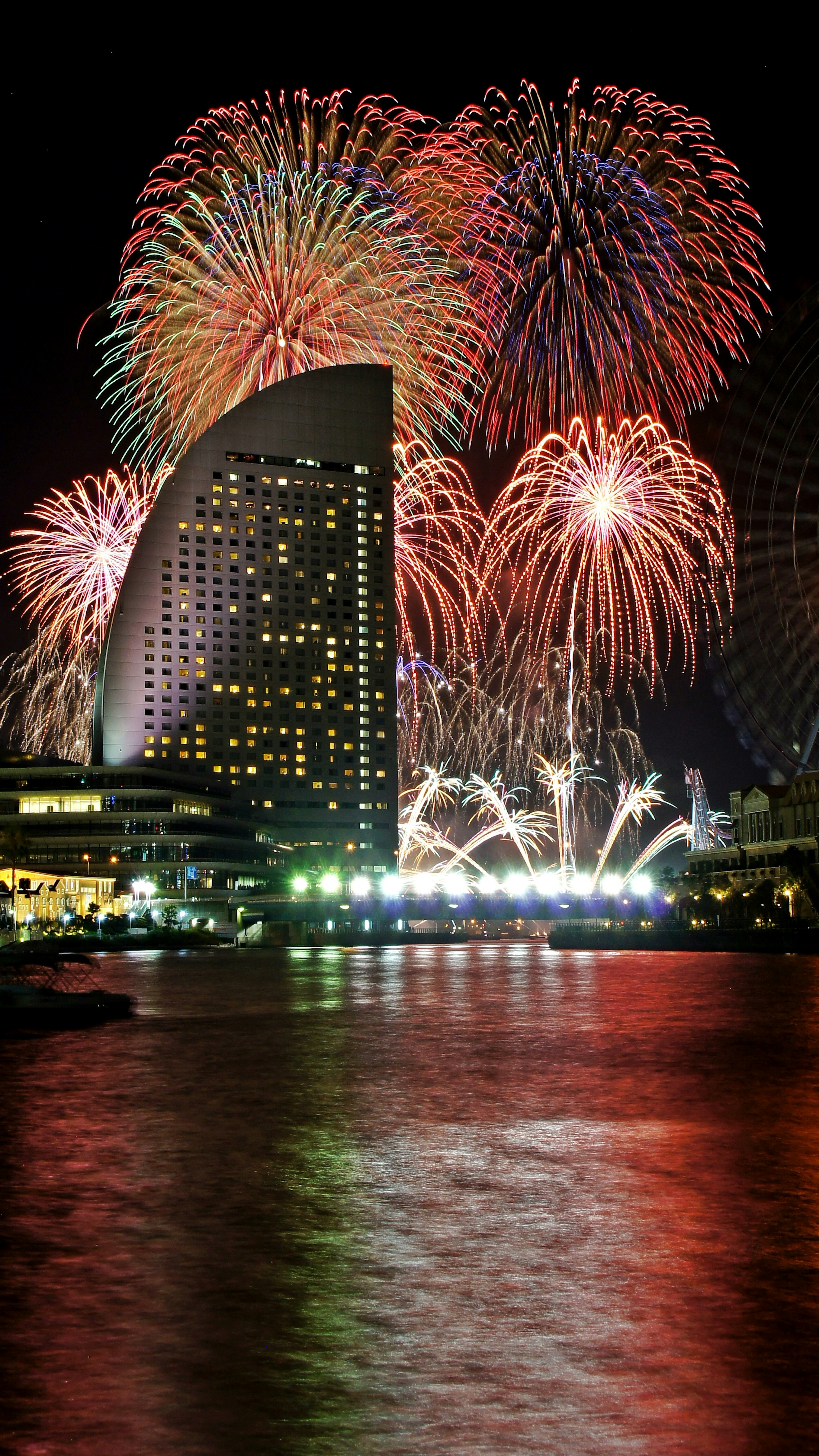 Colorful fireworks exploding in the night sky with a skyscraper silhouette