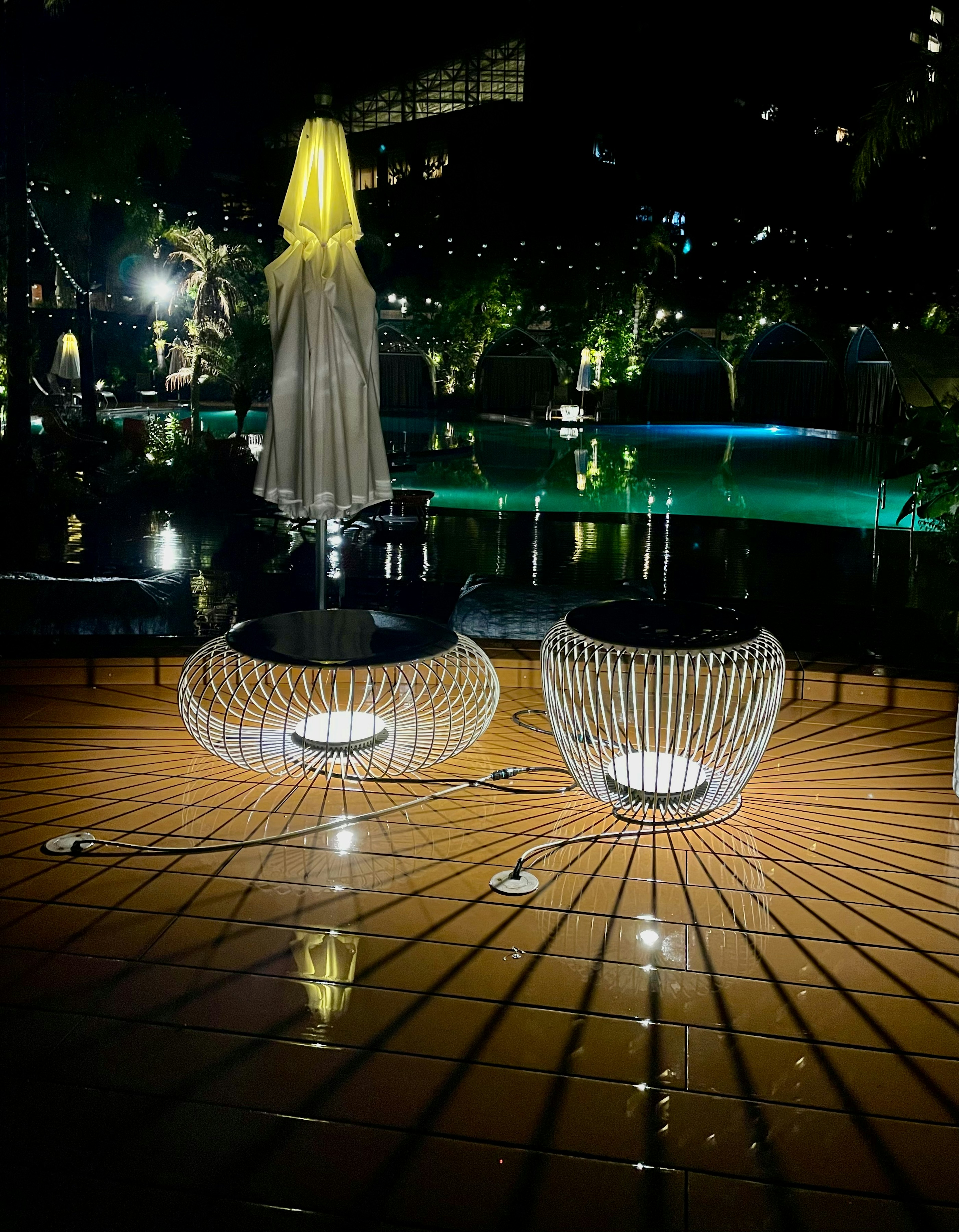 Stylish chairs and umbrella illuminated at a night poolside