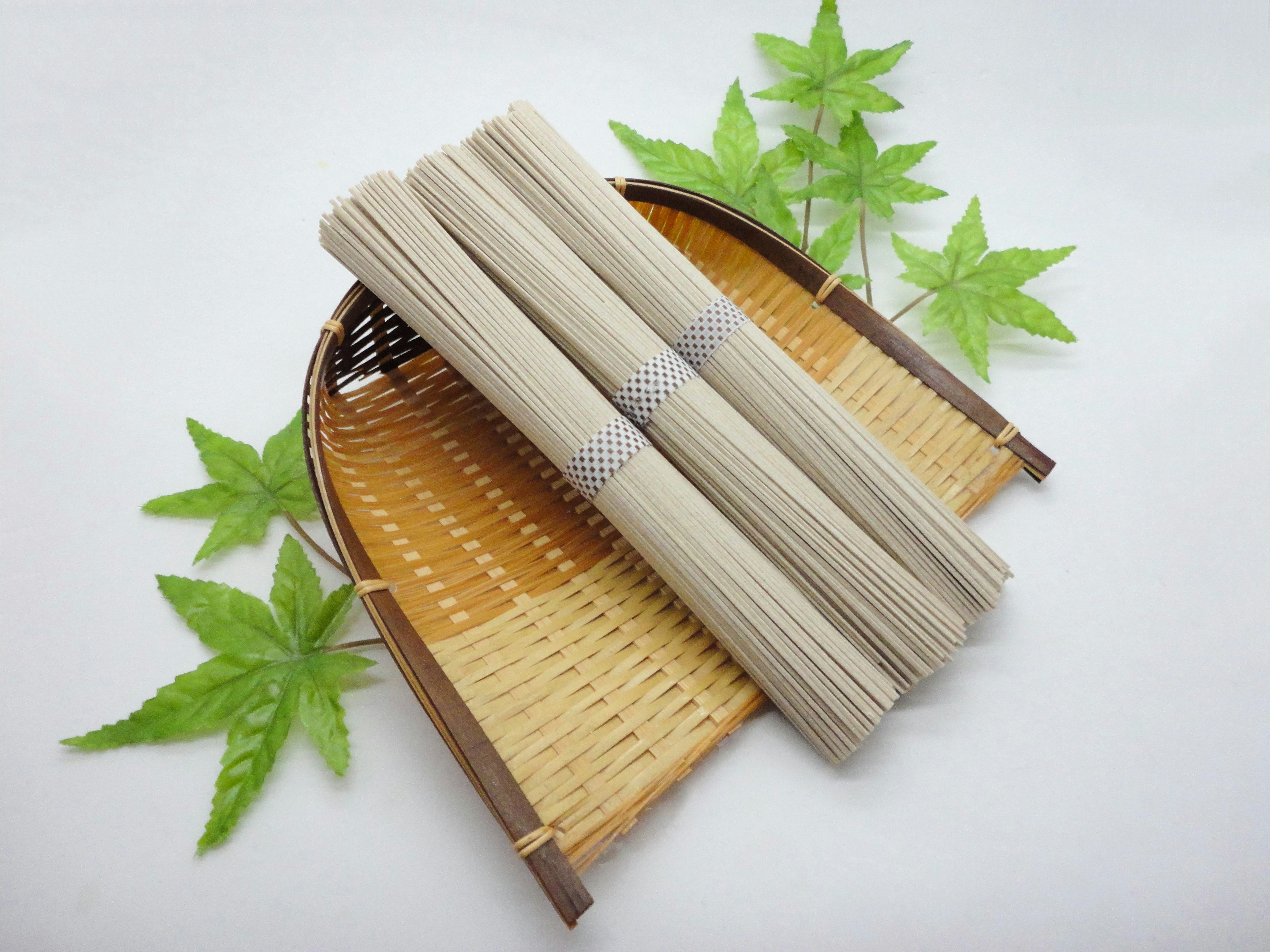 Nouilles soba regroupées sur un panier en bambou avec des feuilles d'érable