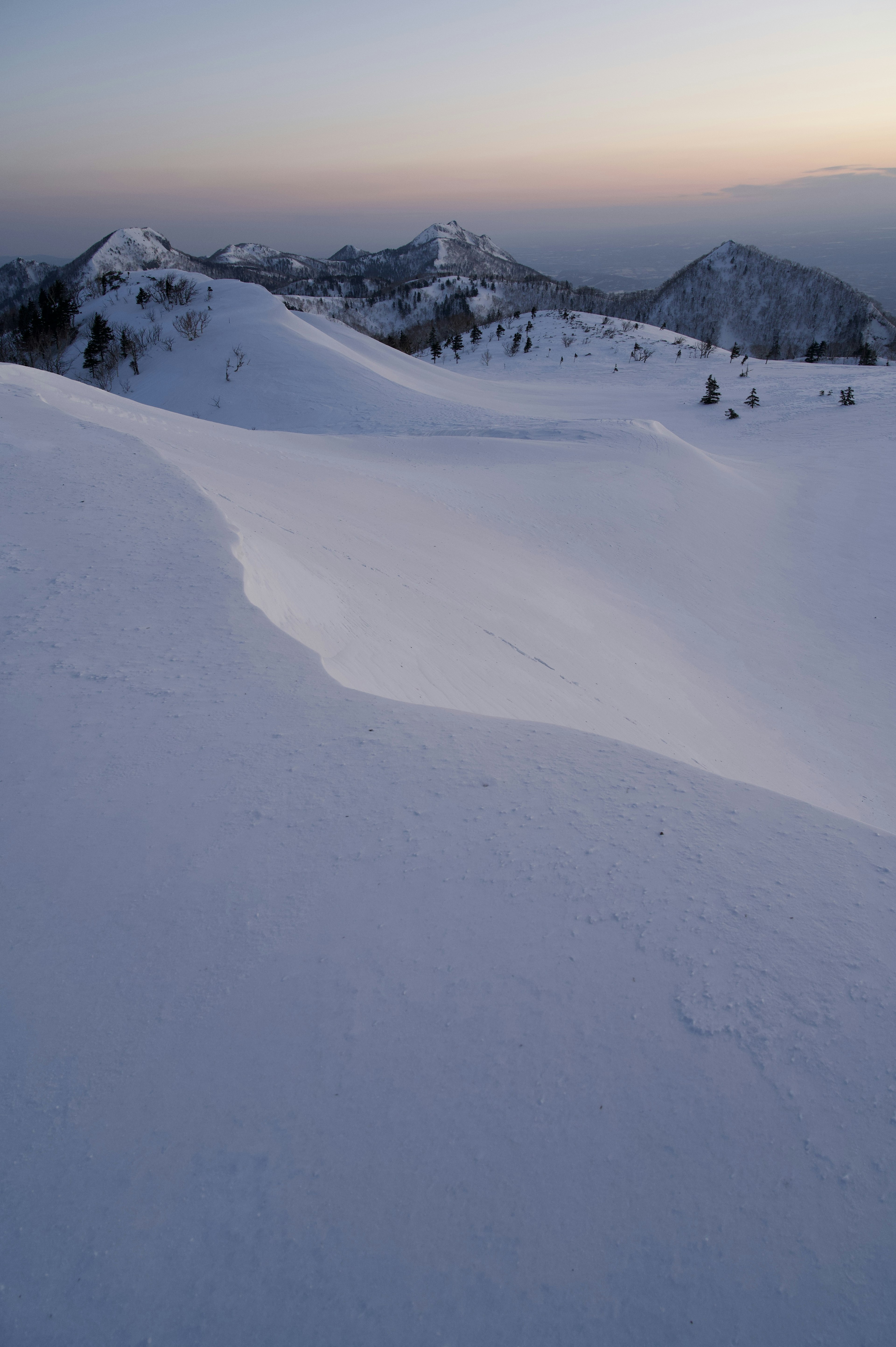 Paisaje montañoso cubierto de nieve con cielo al atardecer