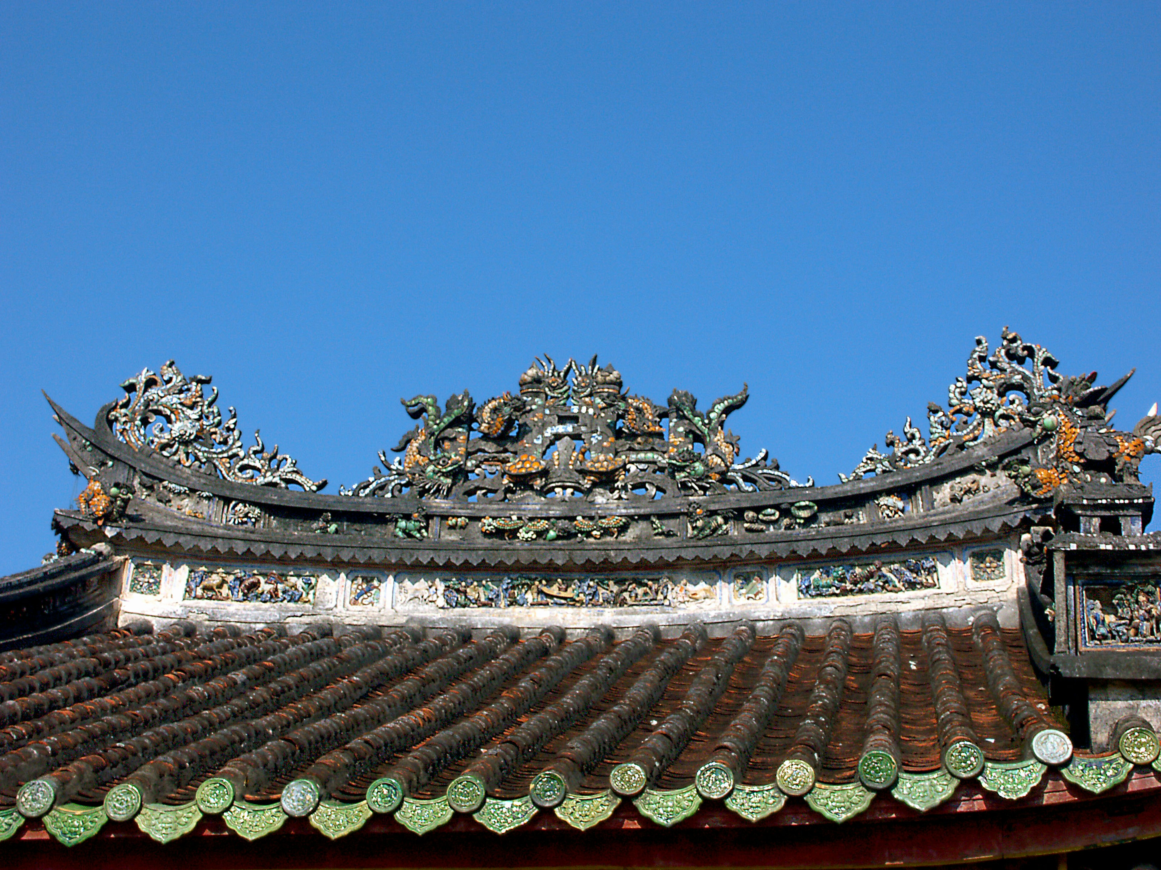 Traditional building roof with intricate decorations under a clear blue sky