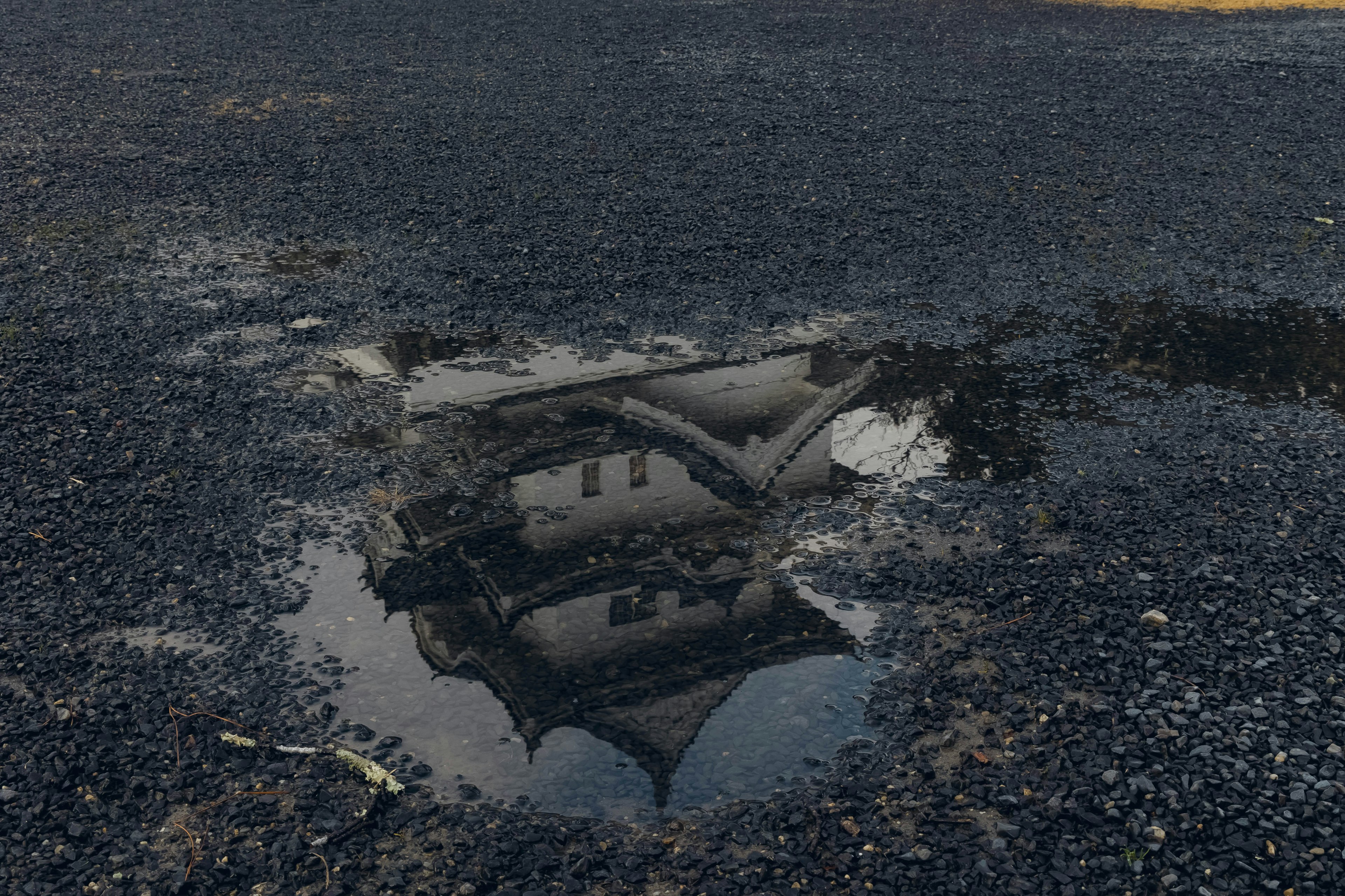 Reflection of a house in a puddle on asphalt