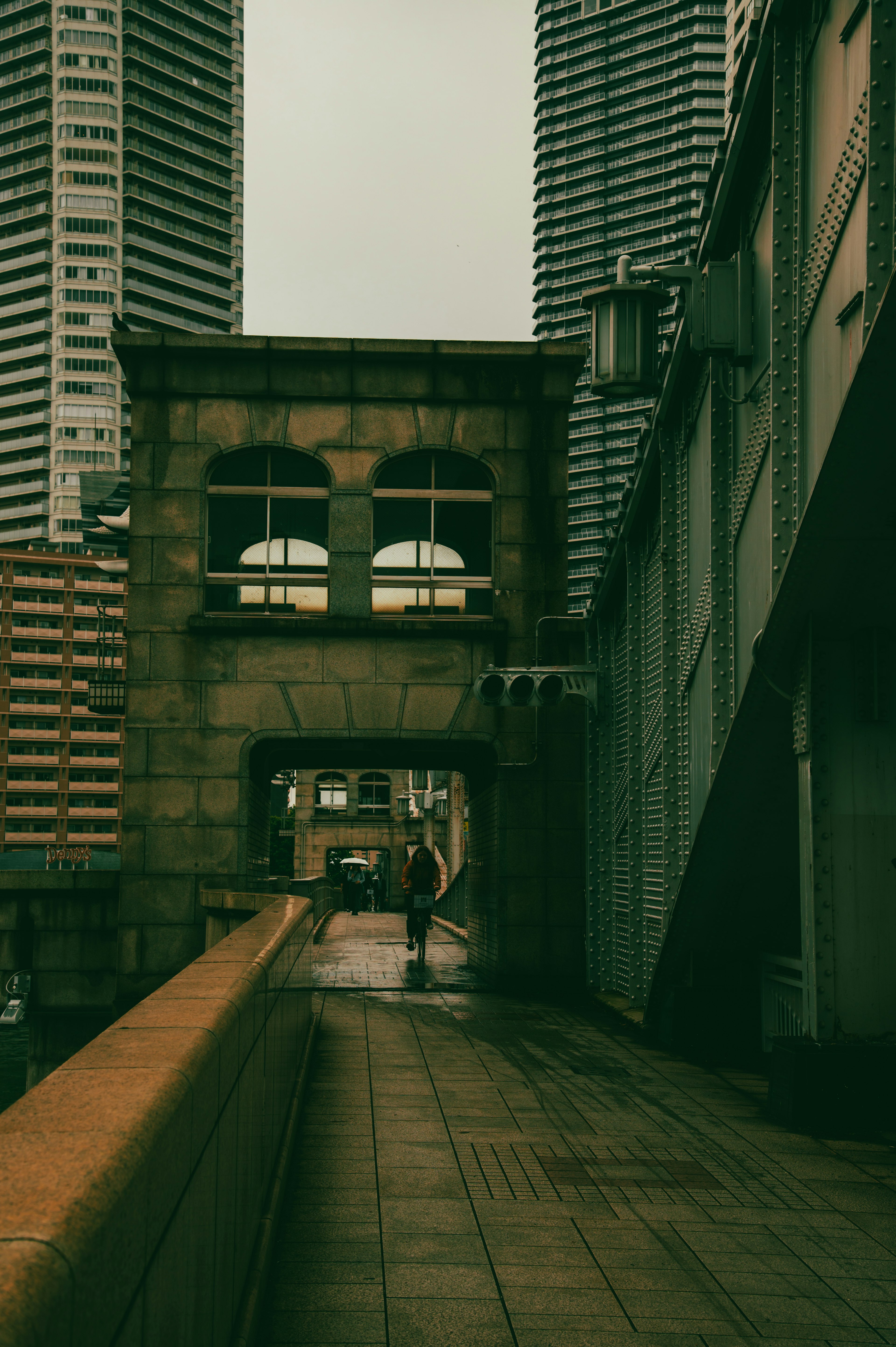 A person walking through an archway structure between skyscrapers