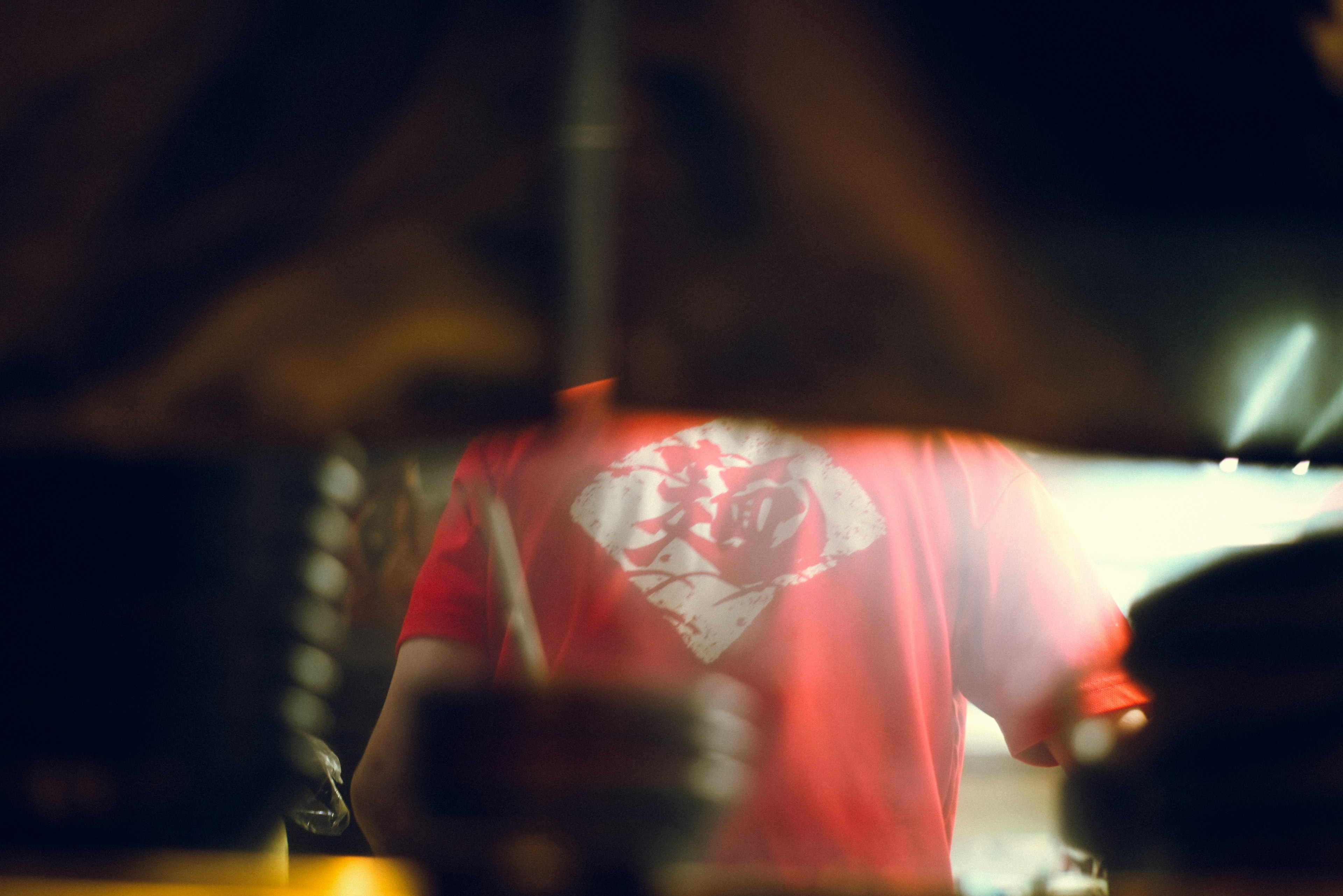 A blurred view of a person wearing a red shirt engaged in an activity