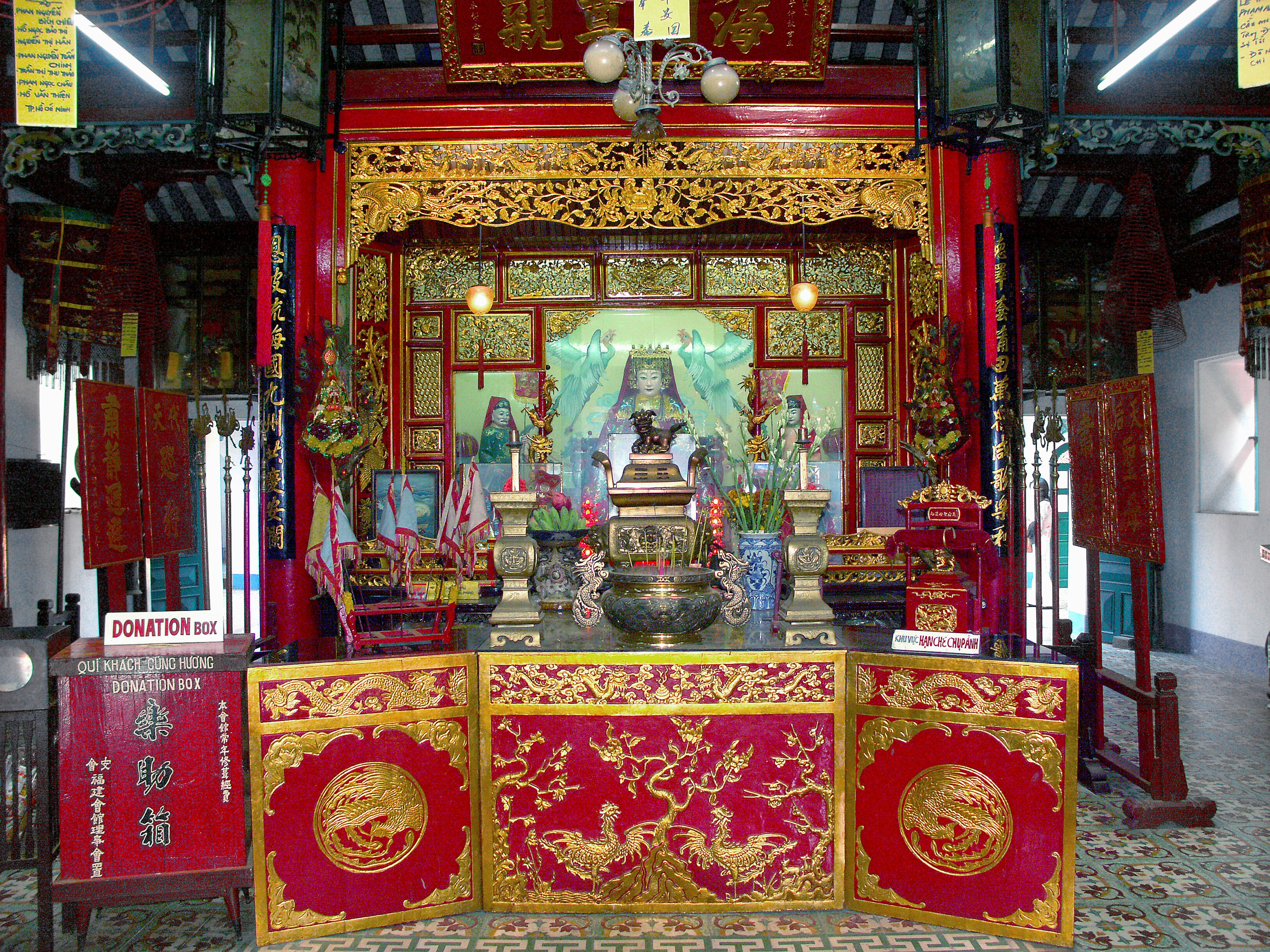 Altar decorado intrincadamente en un templo con colores vibrantes rojo y dorado y varias esculturas y figuras