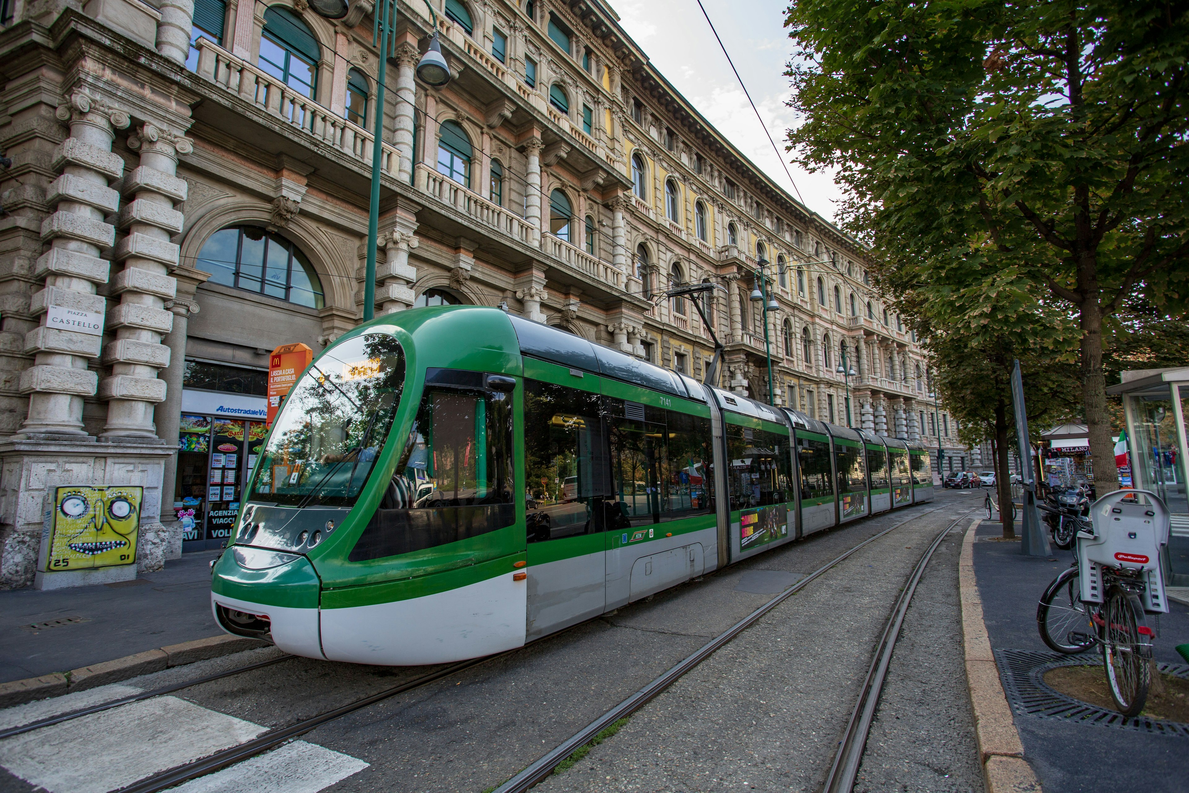 Tram verde che corre lungo una strada curvilinea in un contesto urbano