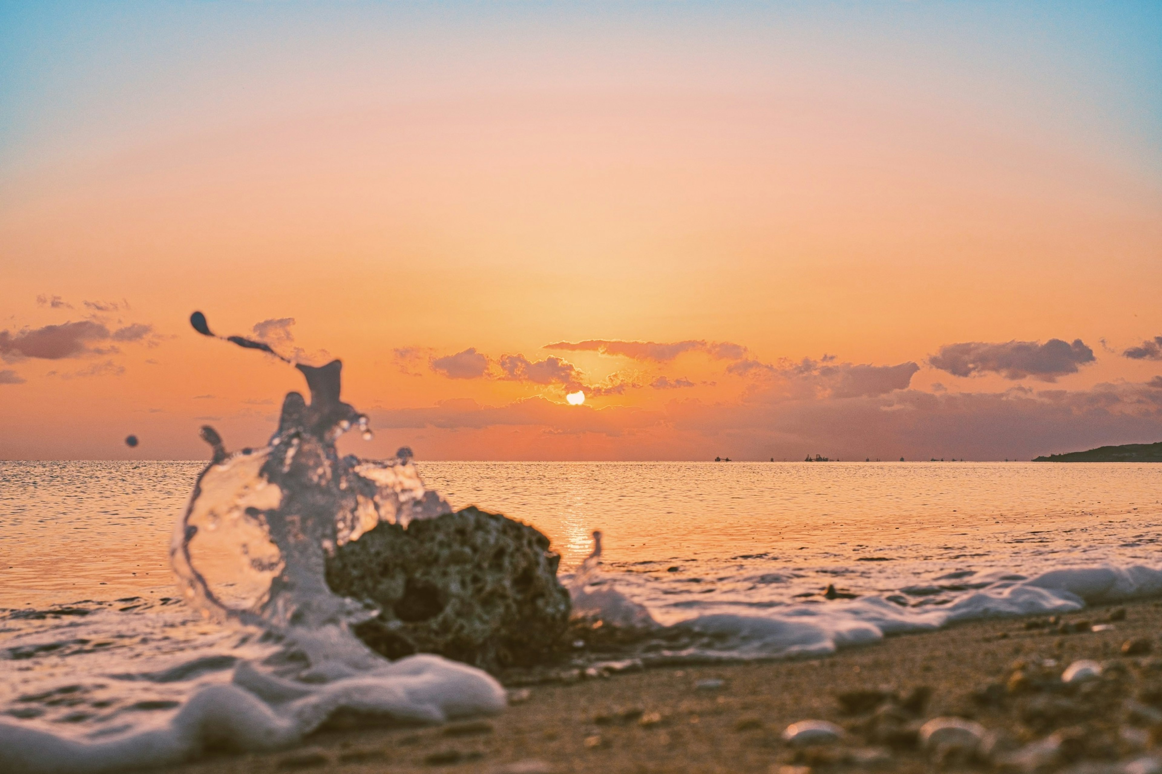 Sonnenuntergang über dem Ozean mit Wellen, die am Ufer spritzen