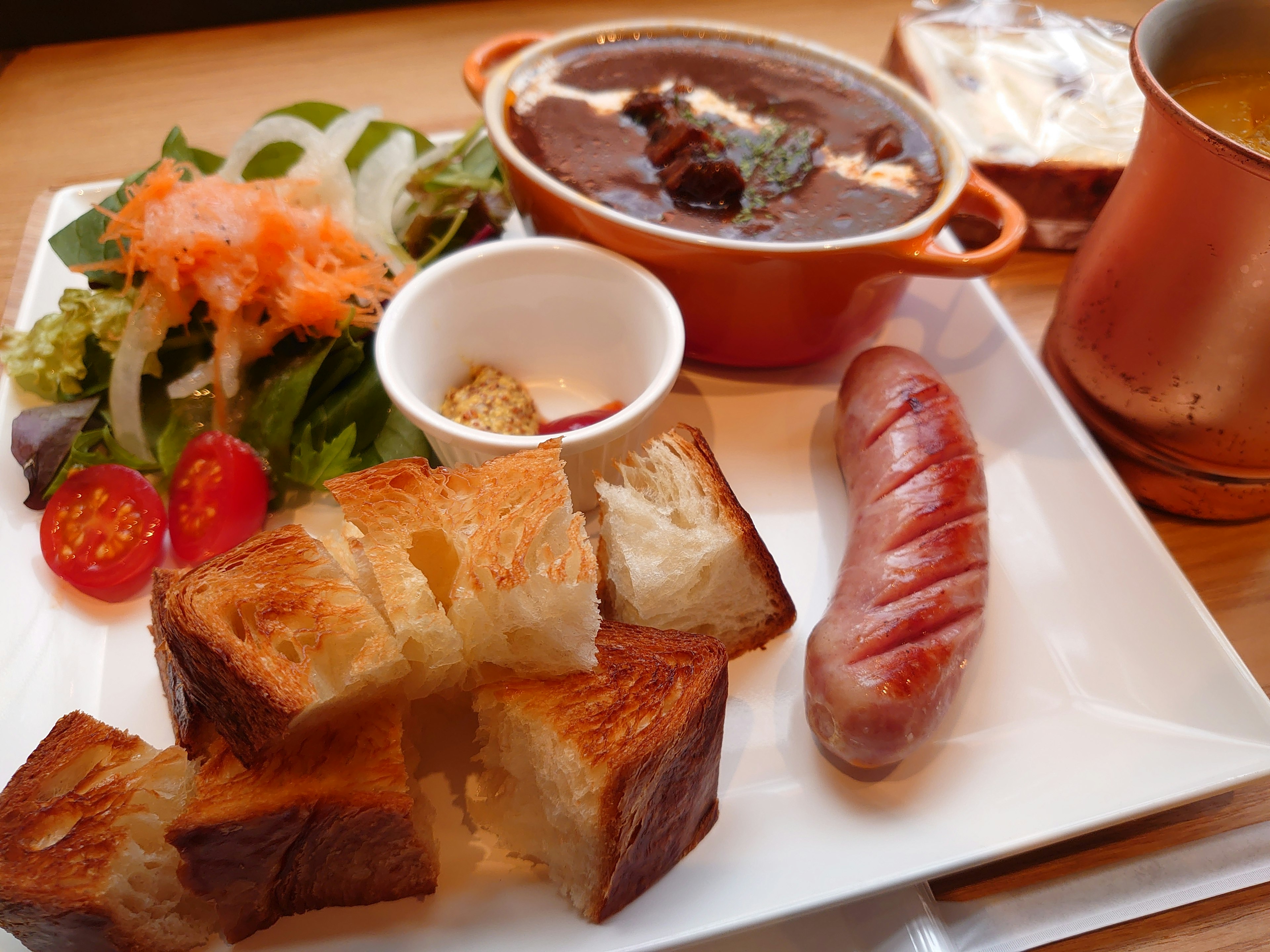 Ein köstlicher Frühstücksteller mit Salat, Wurst, Brot und Eintopf