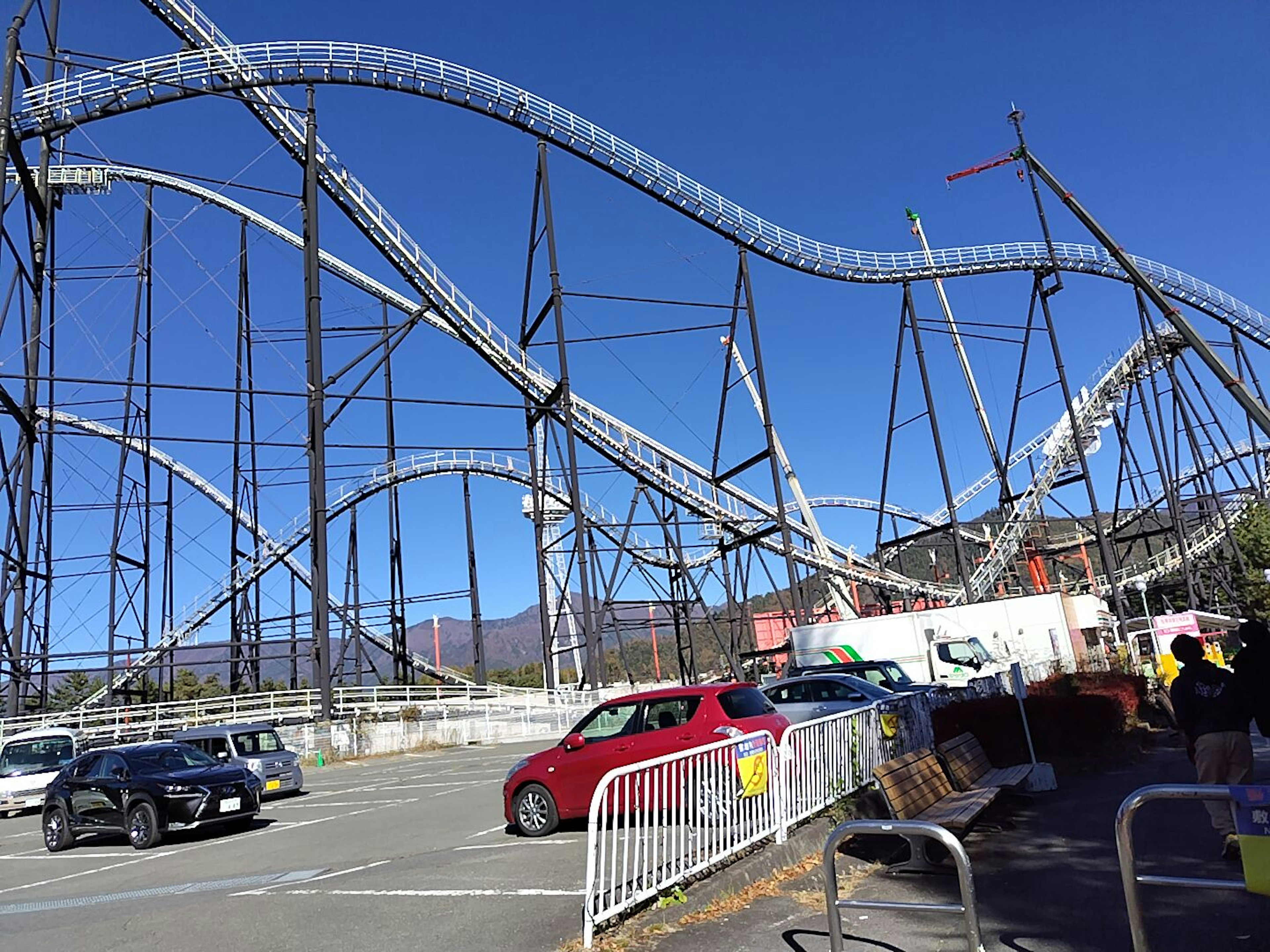 Achterbahn im Freizeitpark mit Autos im Vordergrund