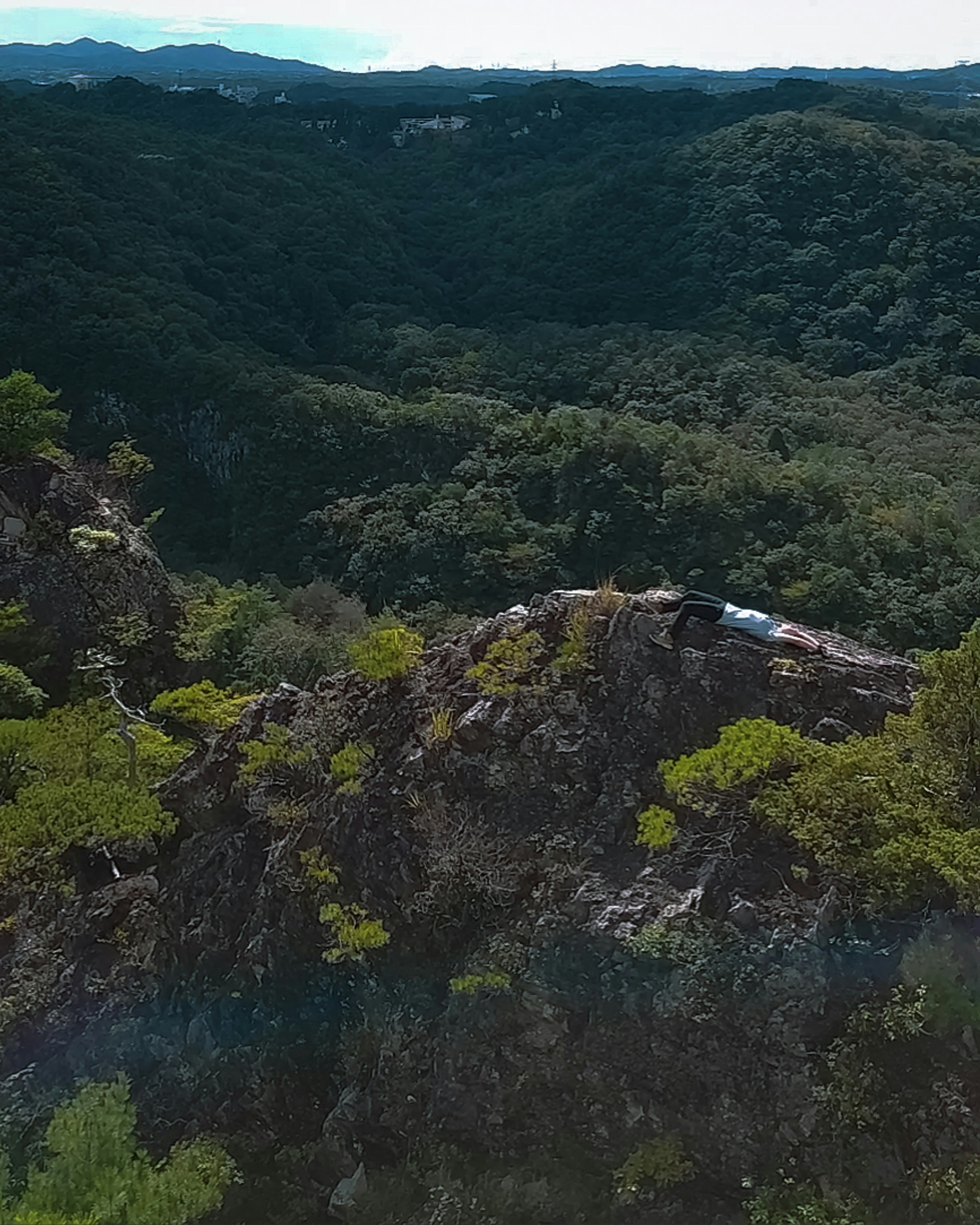 A scenic view of lush green mountains with a vehicle on a rocky outcrop