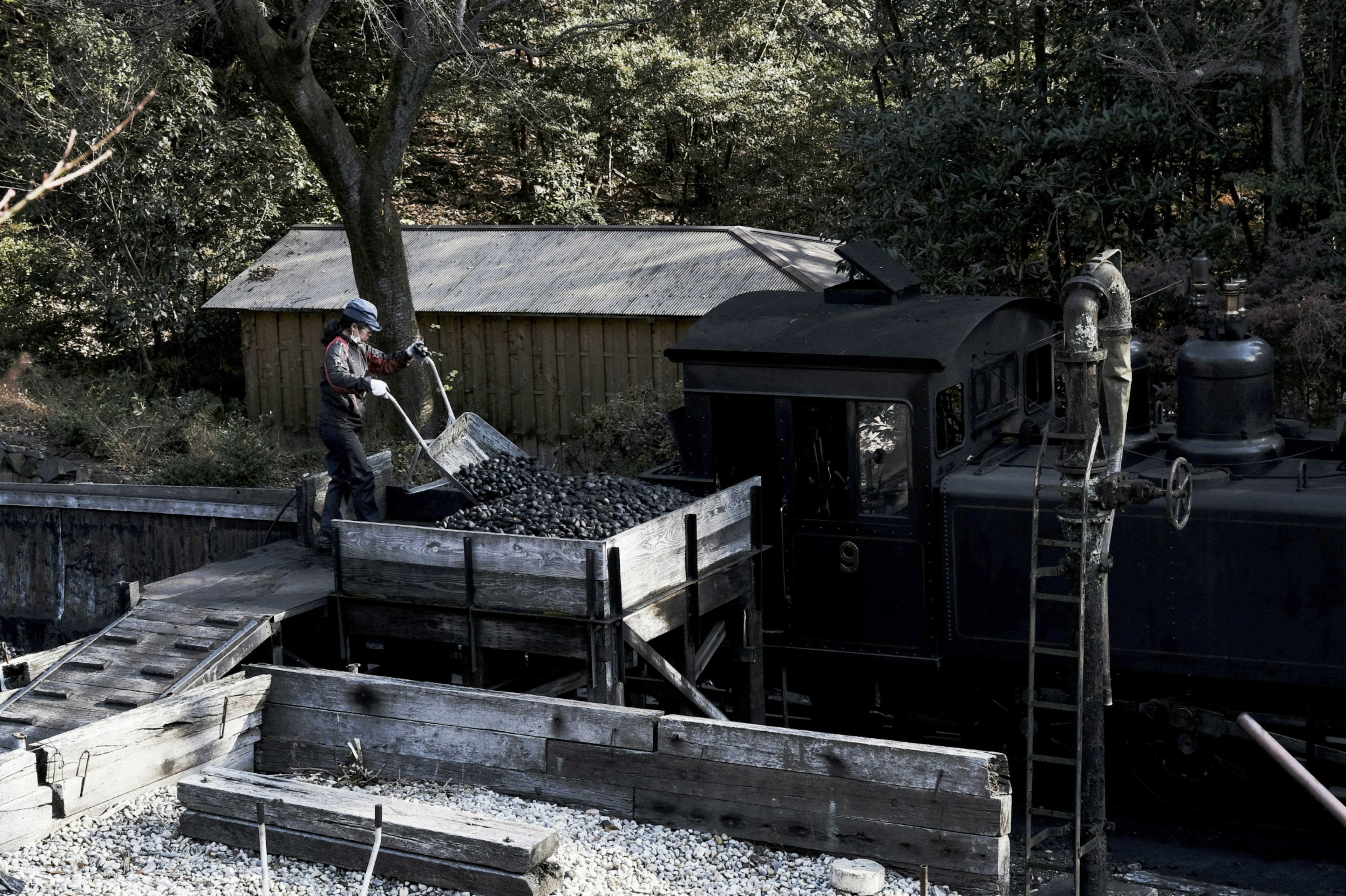 Lavoratori che caricano carbone su una vecchia locomotiva a vapore