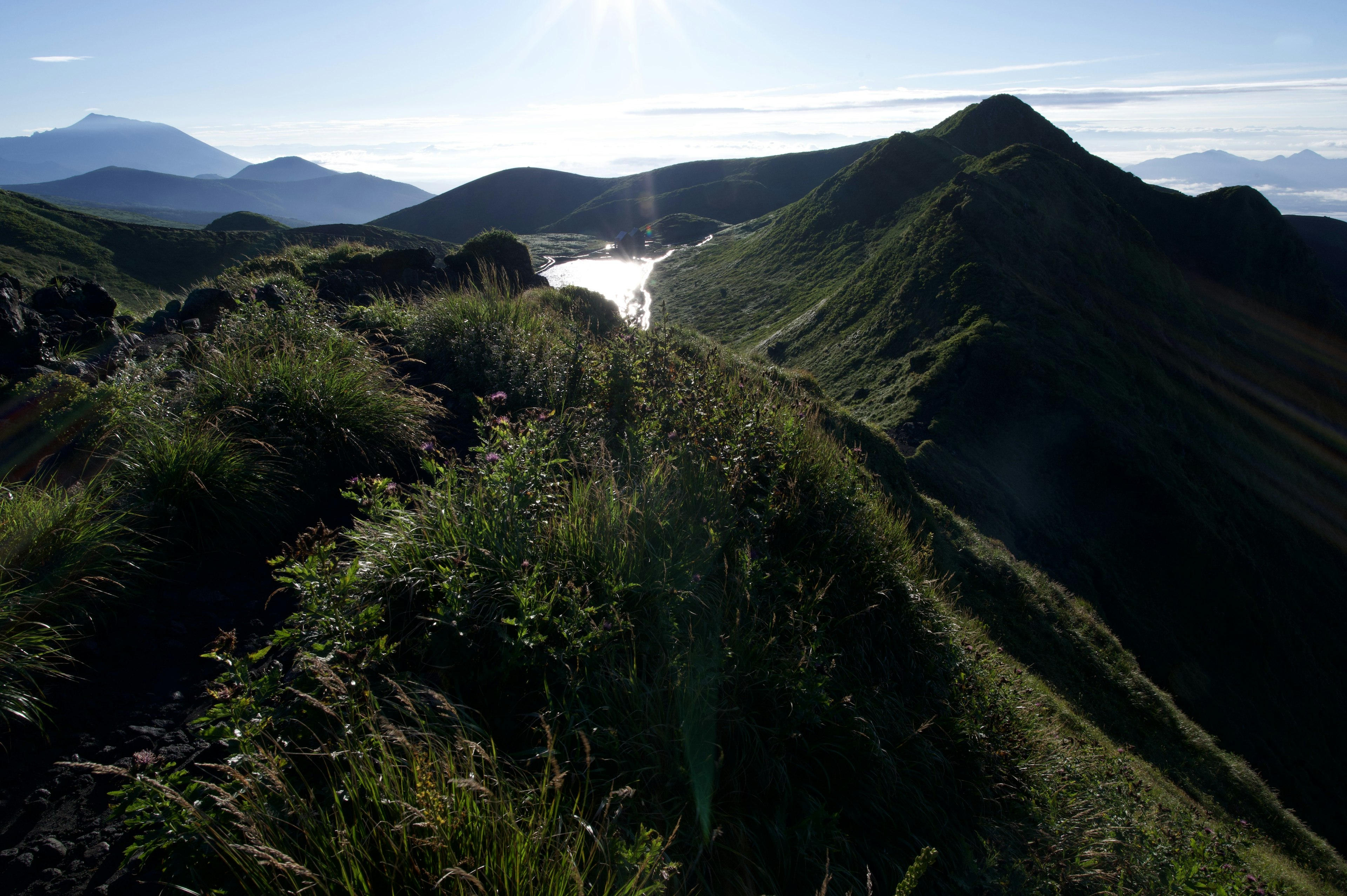 Malersicher Blick von einem Bergrücken mit üppiger Vegetation und fernen Gipfeln