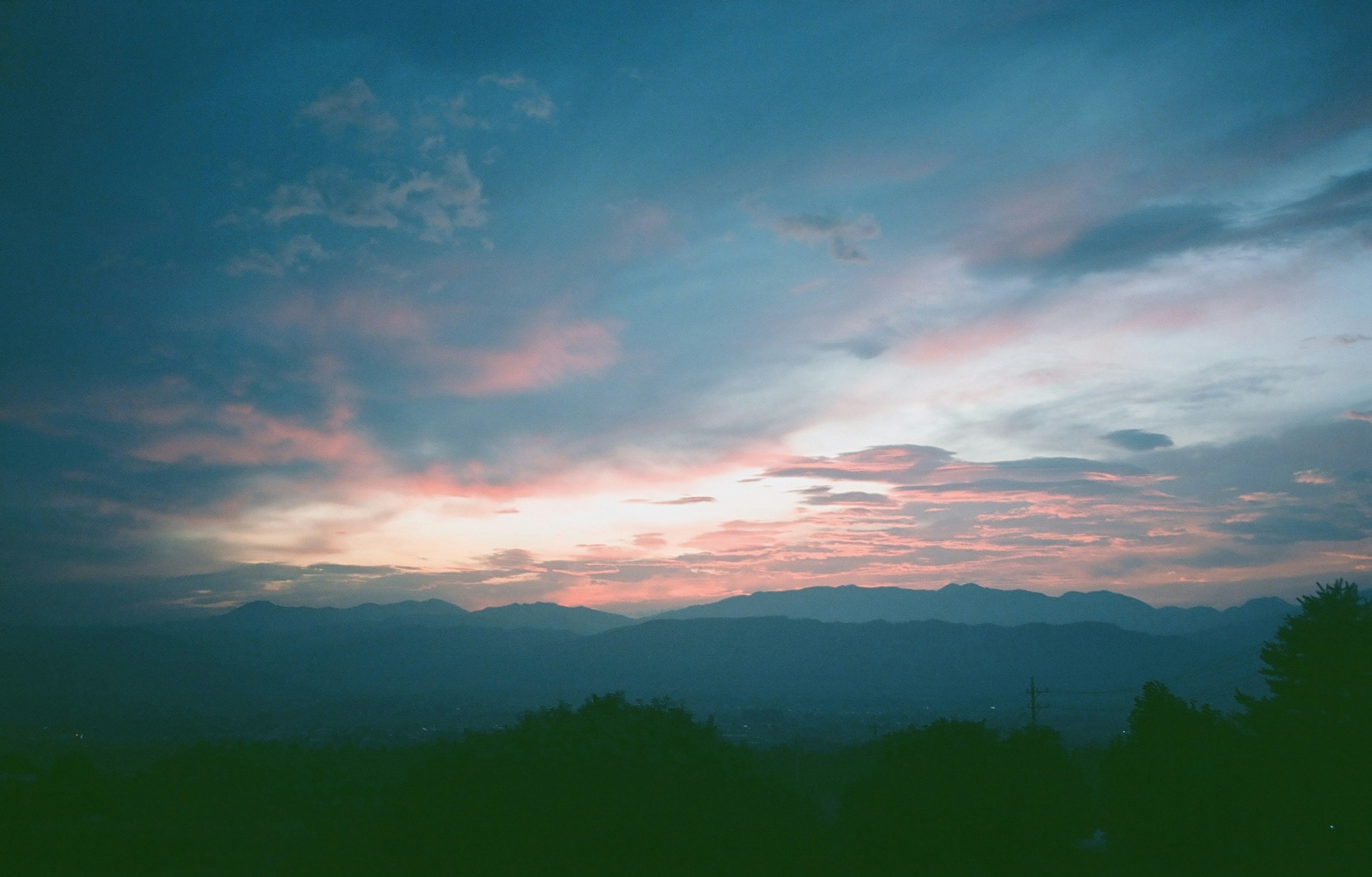 青い空に夕焼けの美しい色合いが広がる山の風景