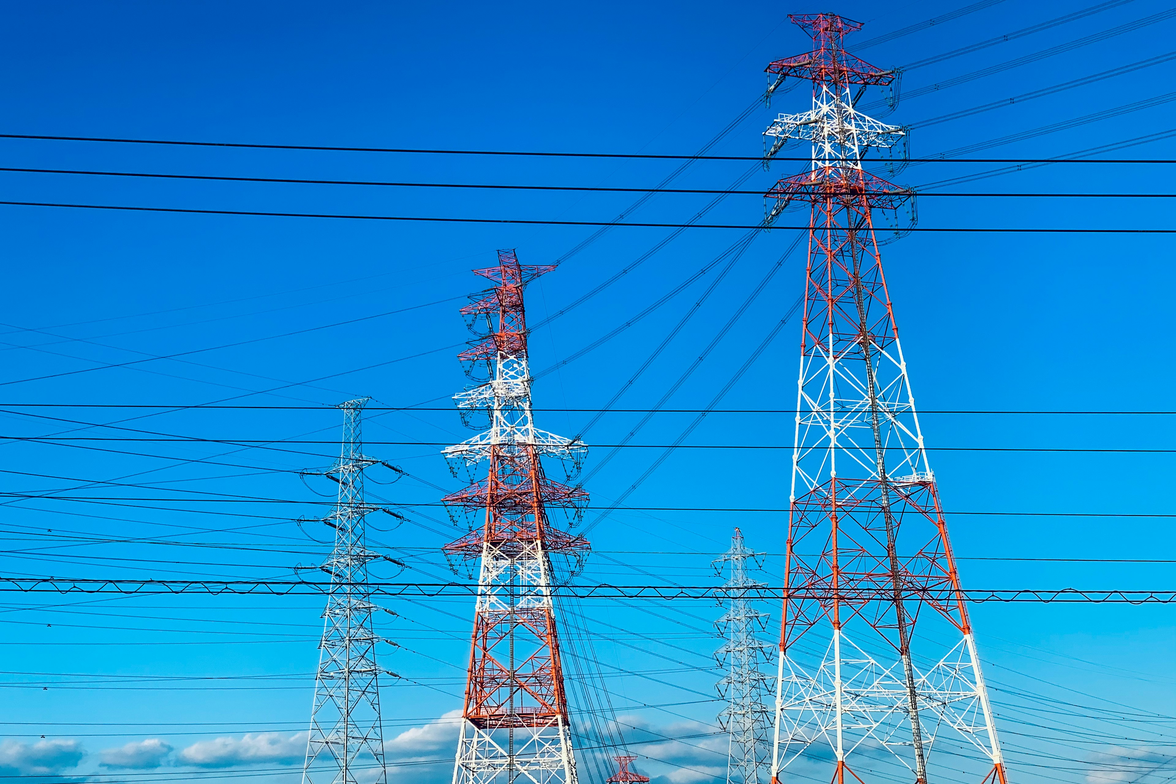 青空の下に立つ電柱群と電線のクリアな視界