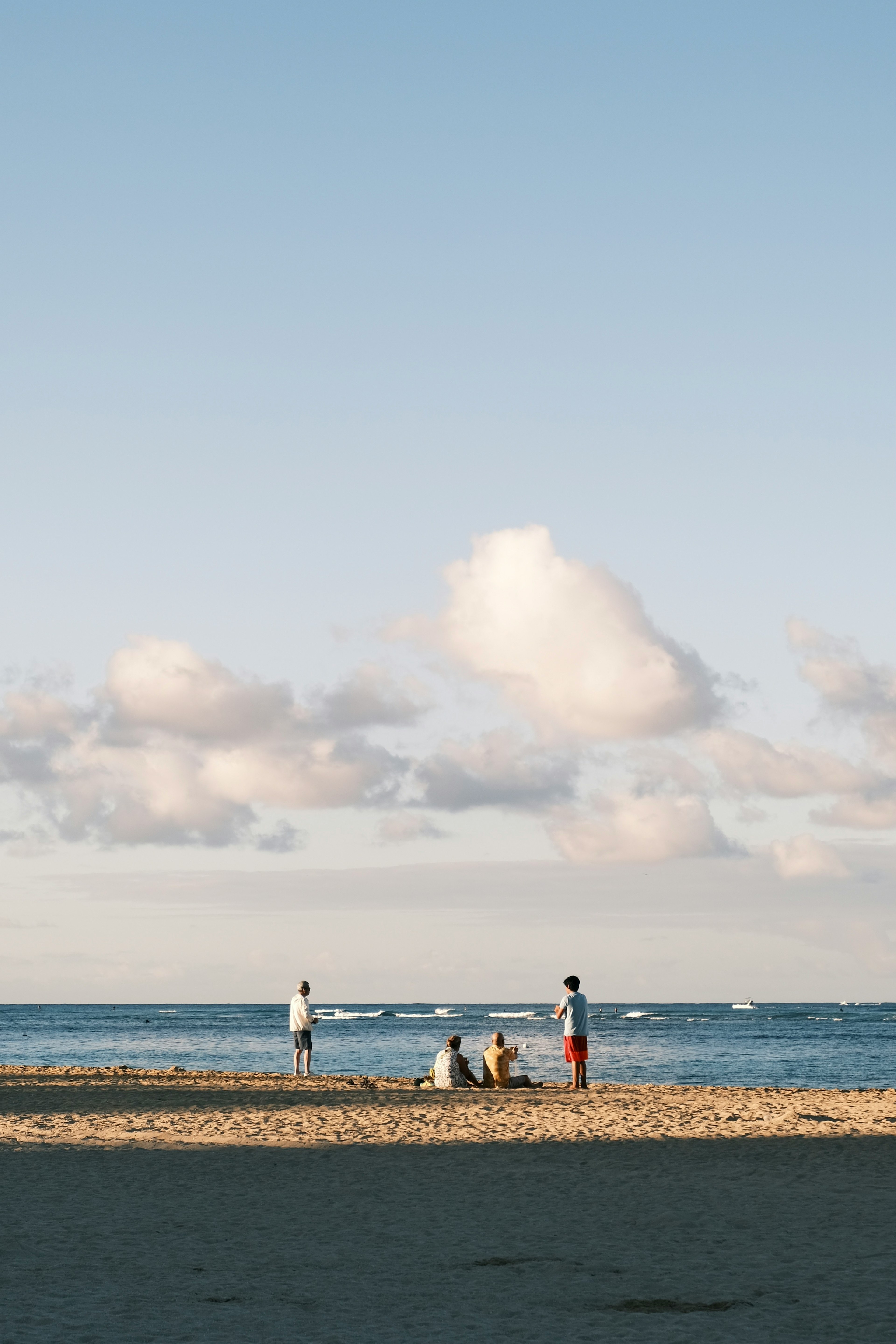 People enjoying a beach day under a blue sky with clouds
