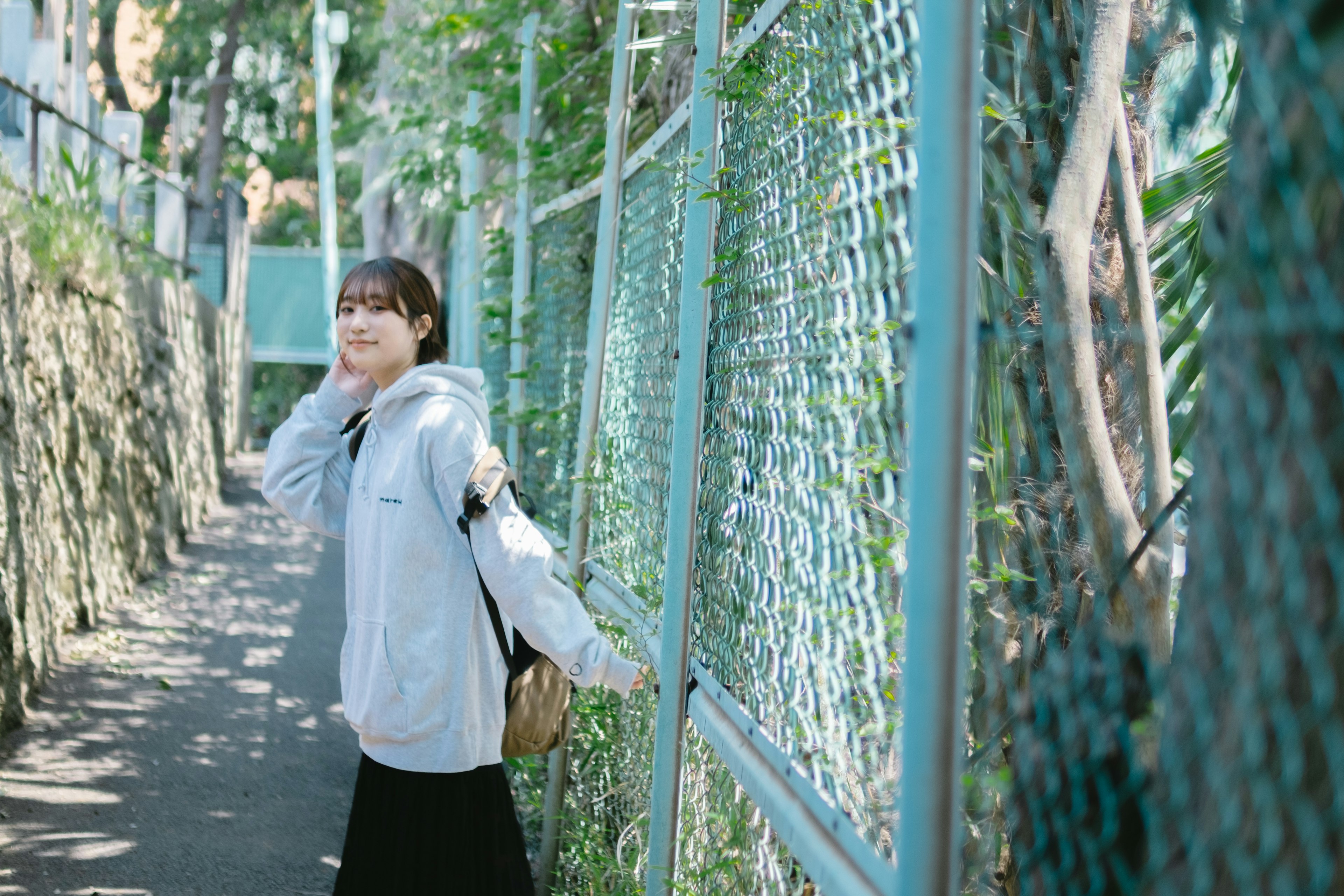 A woman smiling while walking near a blue fence