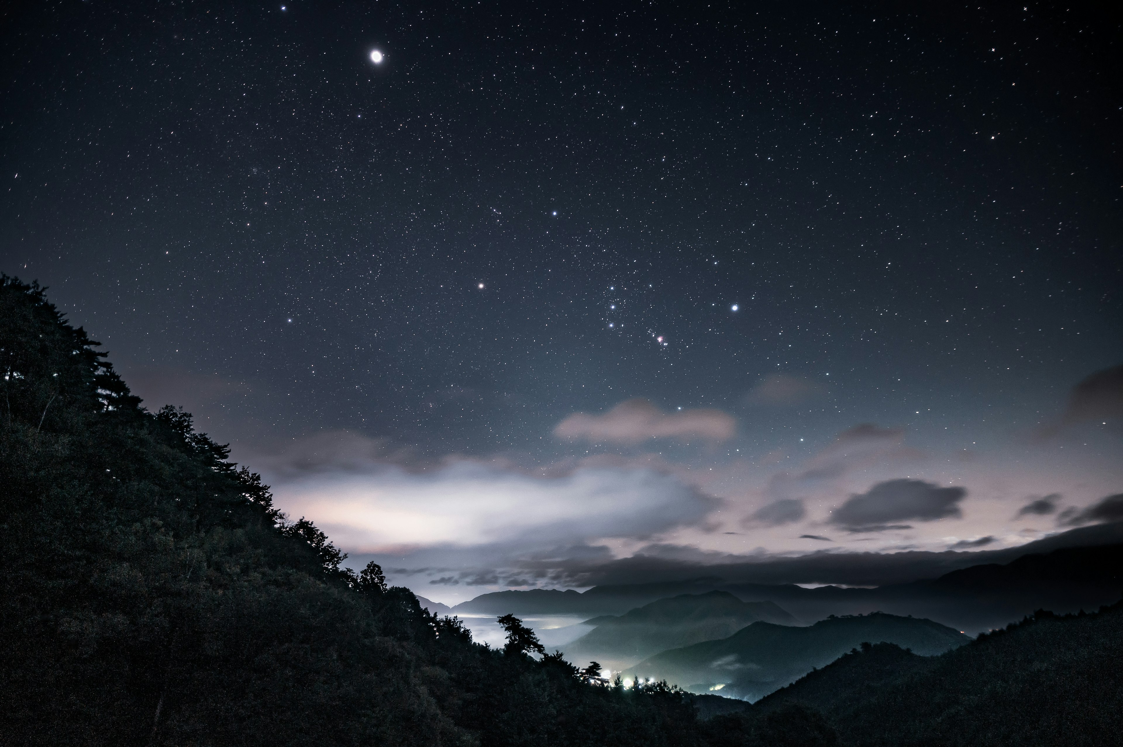 Paesaggio montano sotto un cielo stellato con nuvole di notte