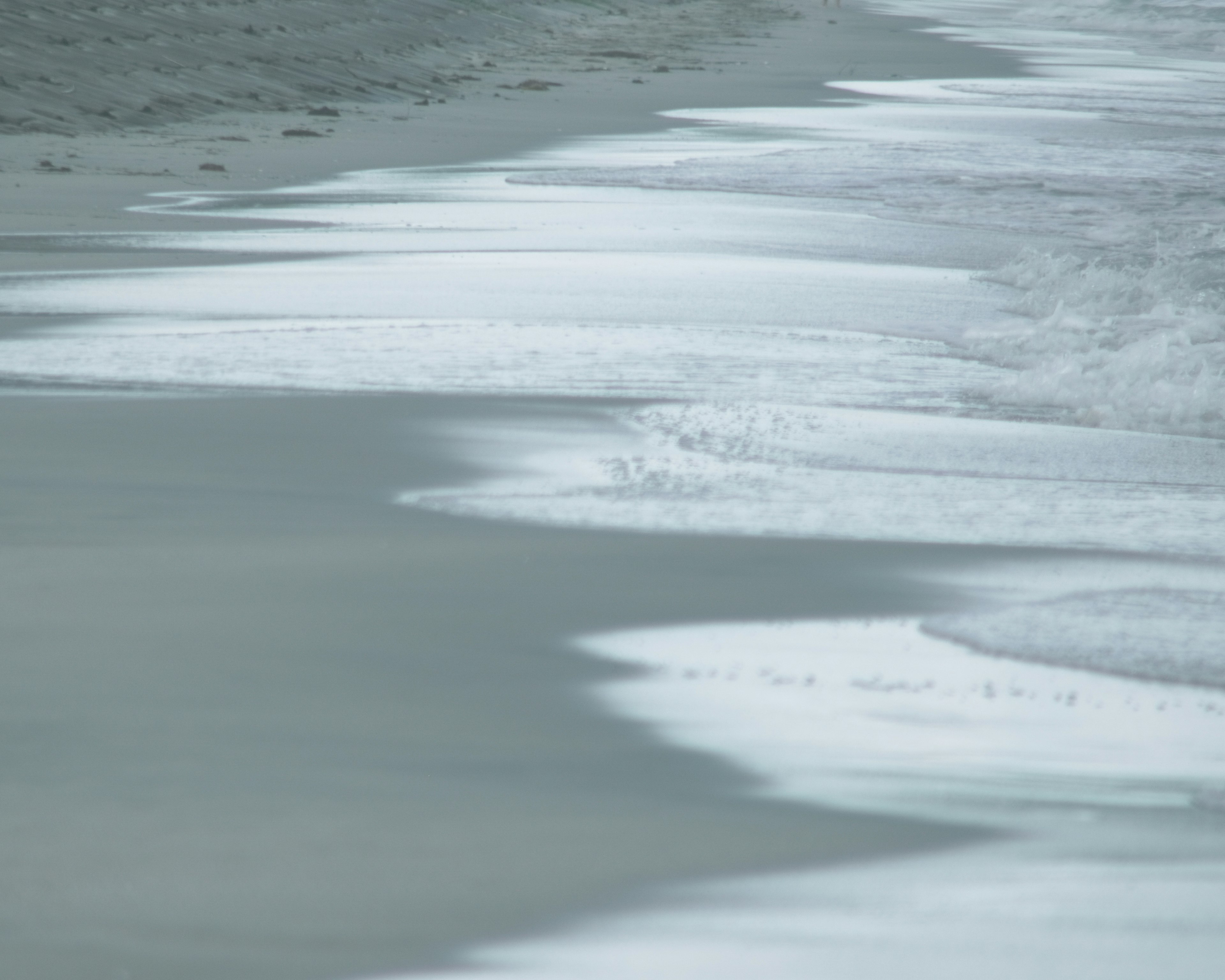 Sanfte Wellen und Schaum, die an einen ruhigen Strand schlagen