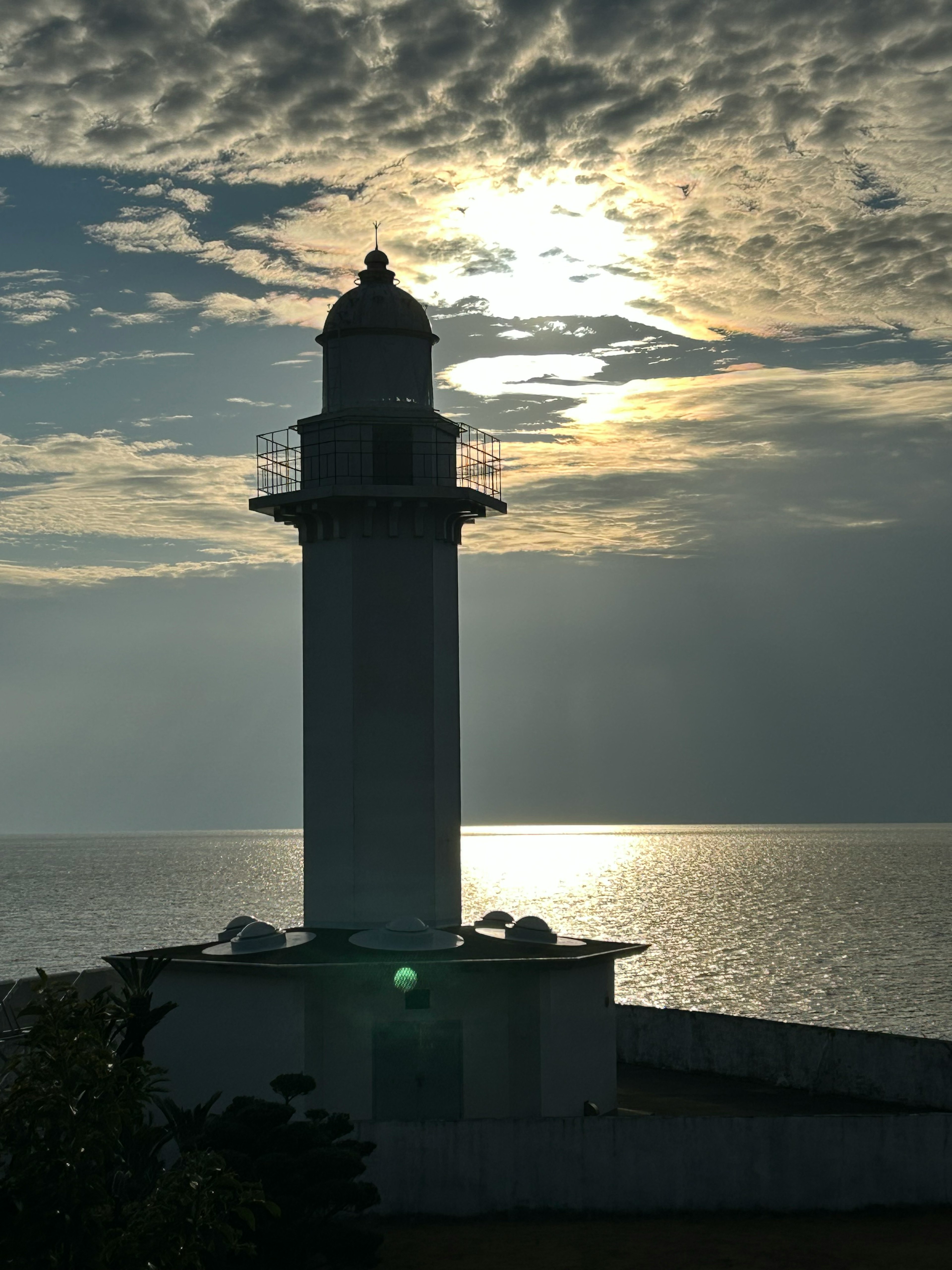 Siluet mercusuar melawan matahari terbenam di laut