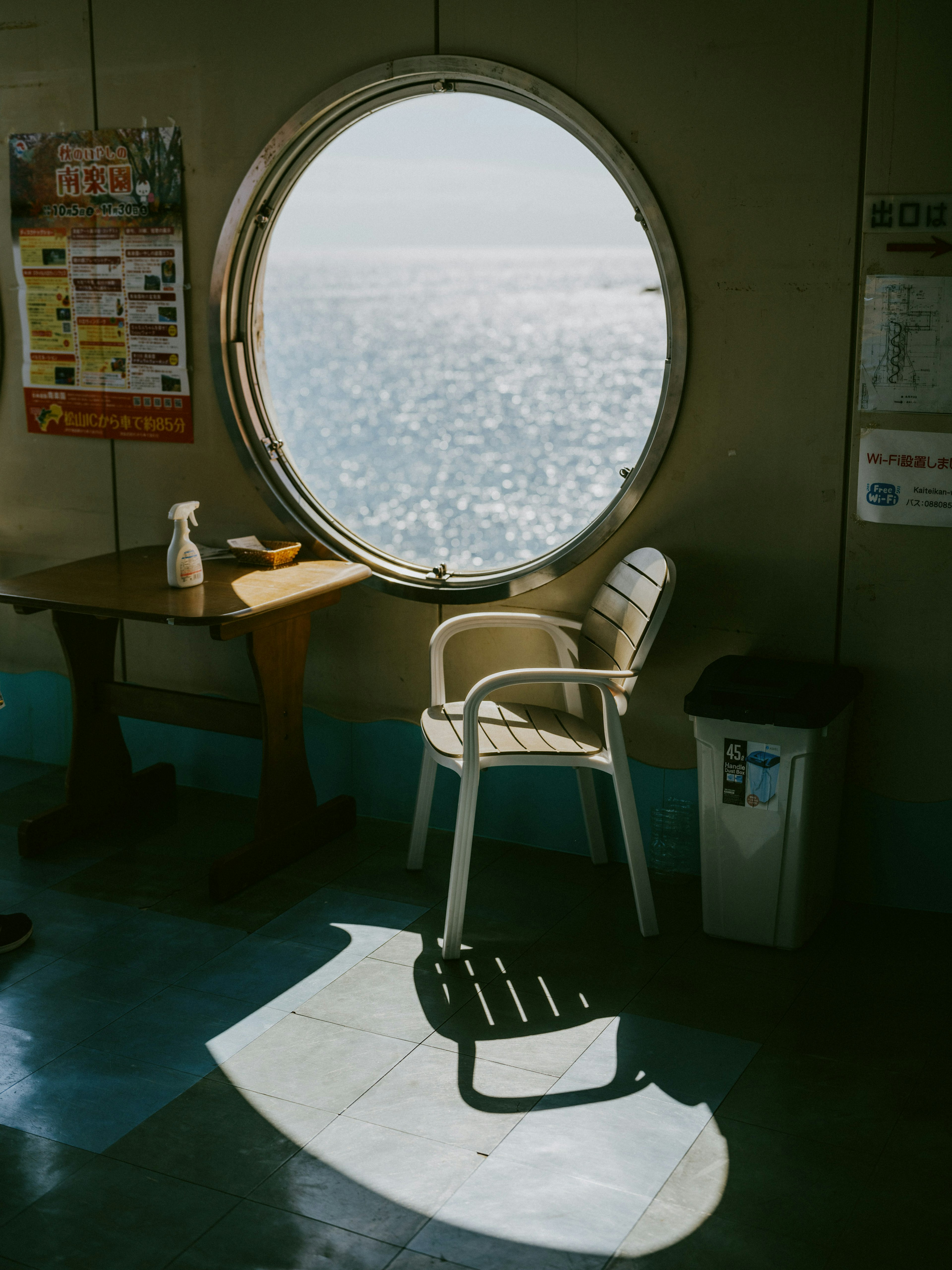 Vue intérieure avec une fenêtre ronde donnant sur la mer et une chaise