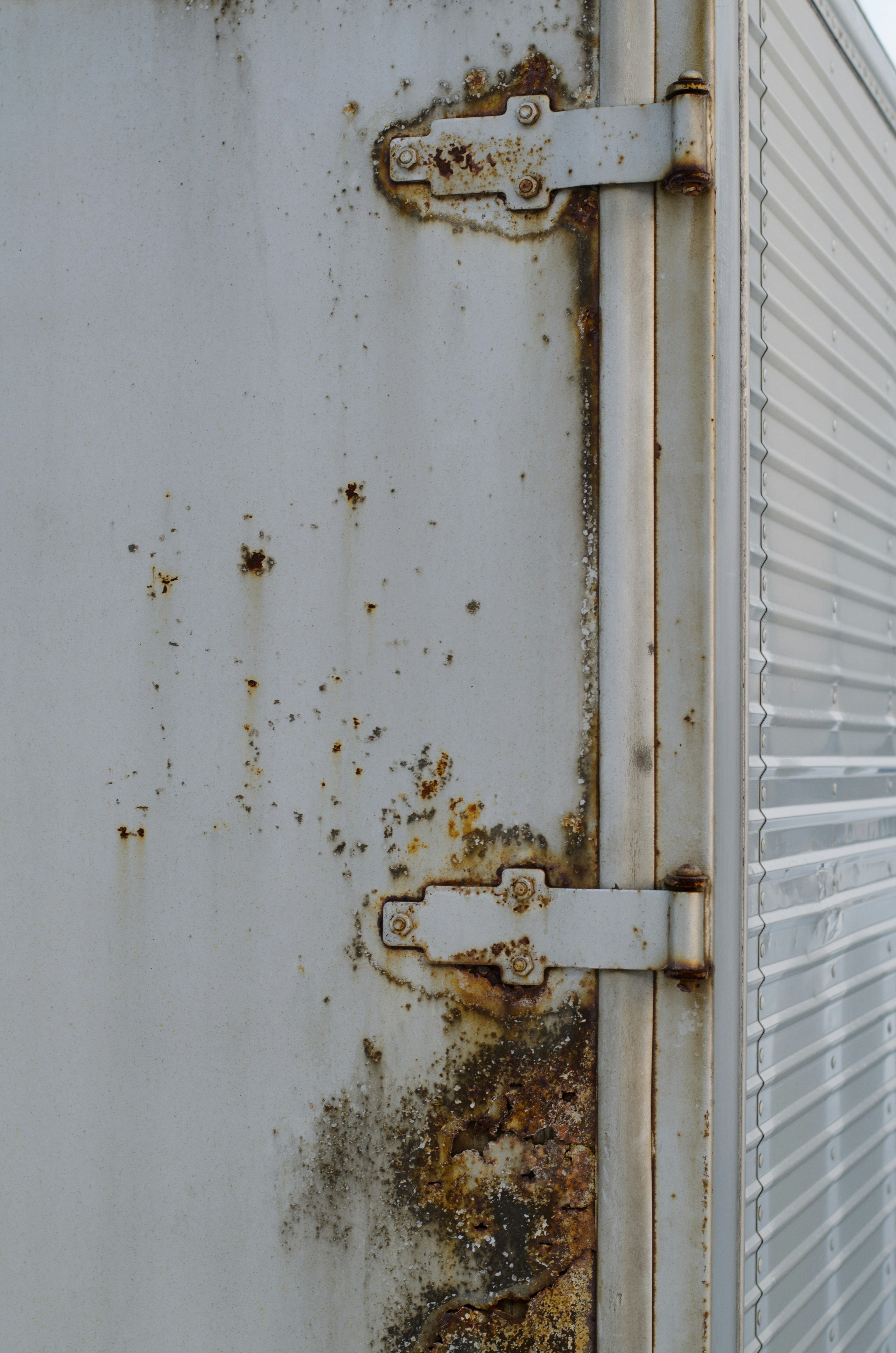 Rusty and dirty sections on the side of a white metal container