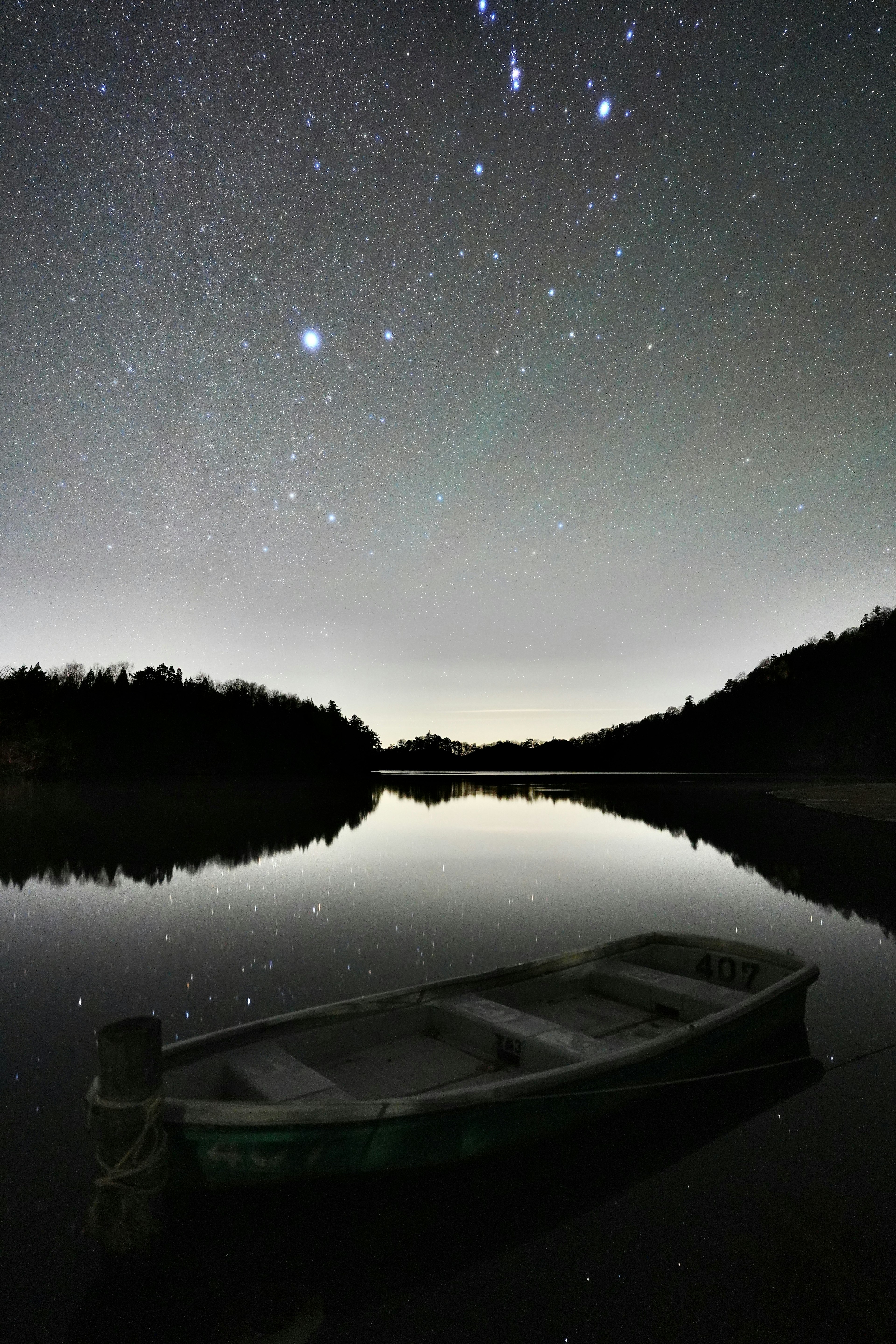 A tranquil lake under a starry sky with a small boat