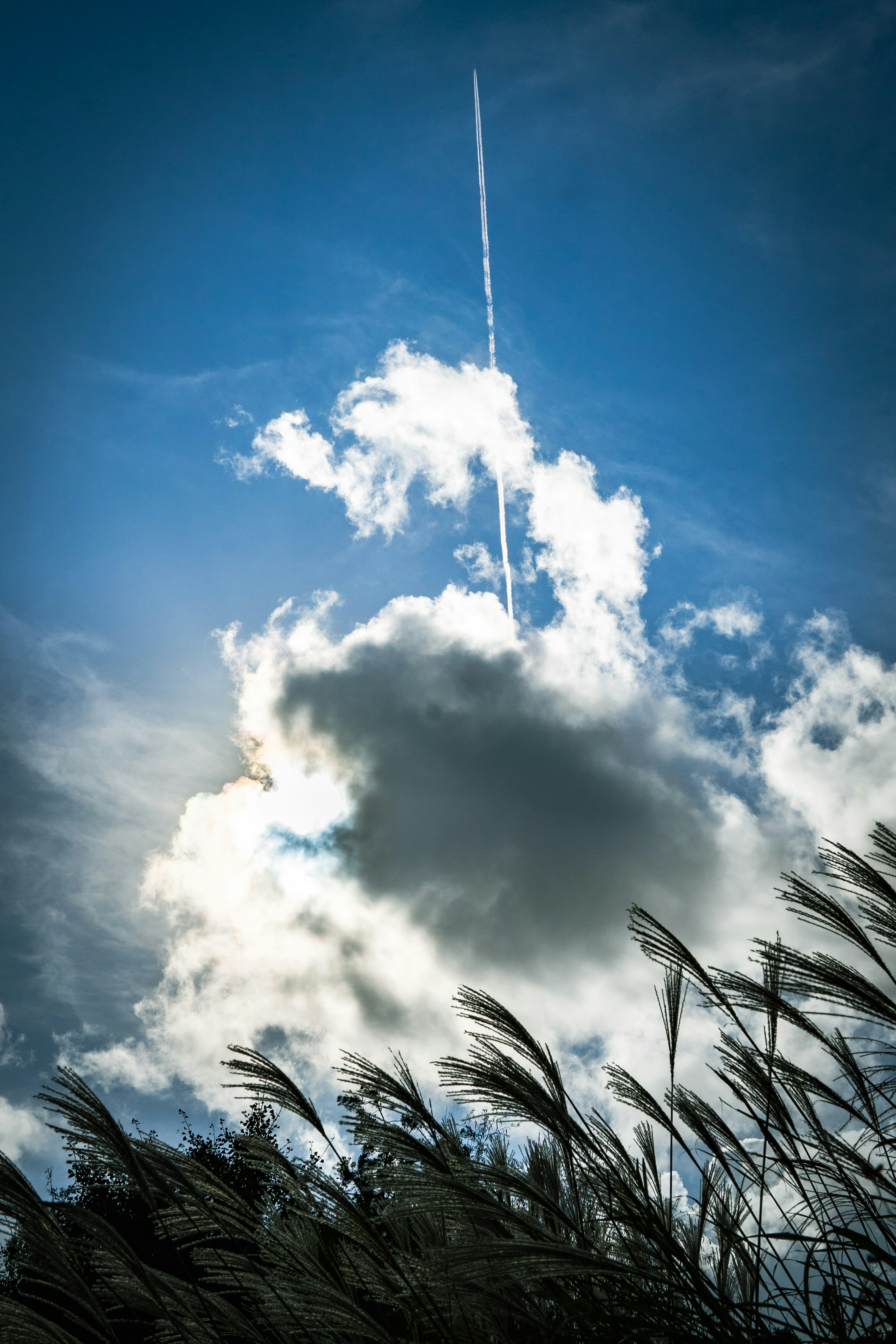 Szenische Aussicht auf Wolken im blauen Himmel mit einer Flugzeugspur