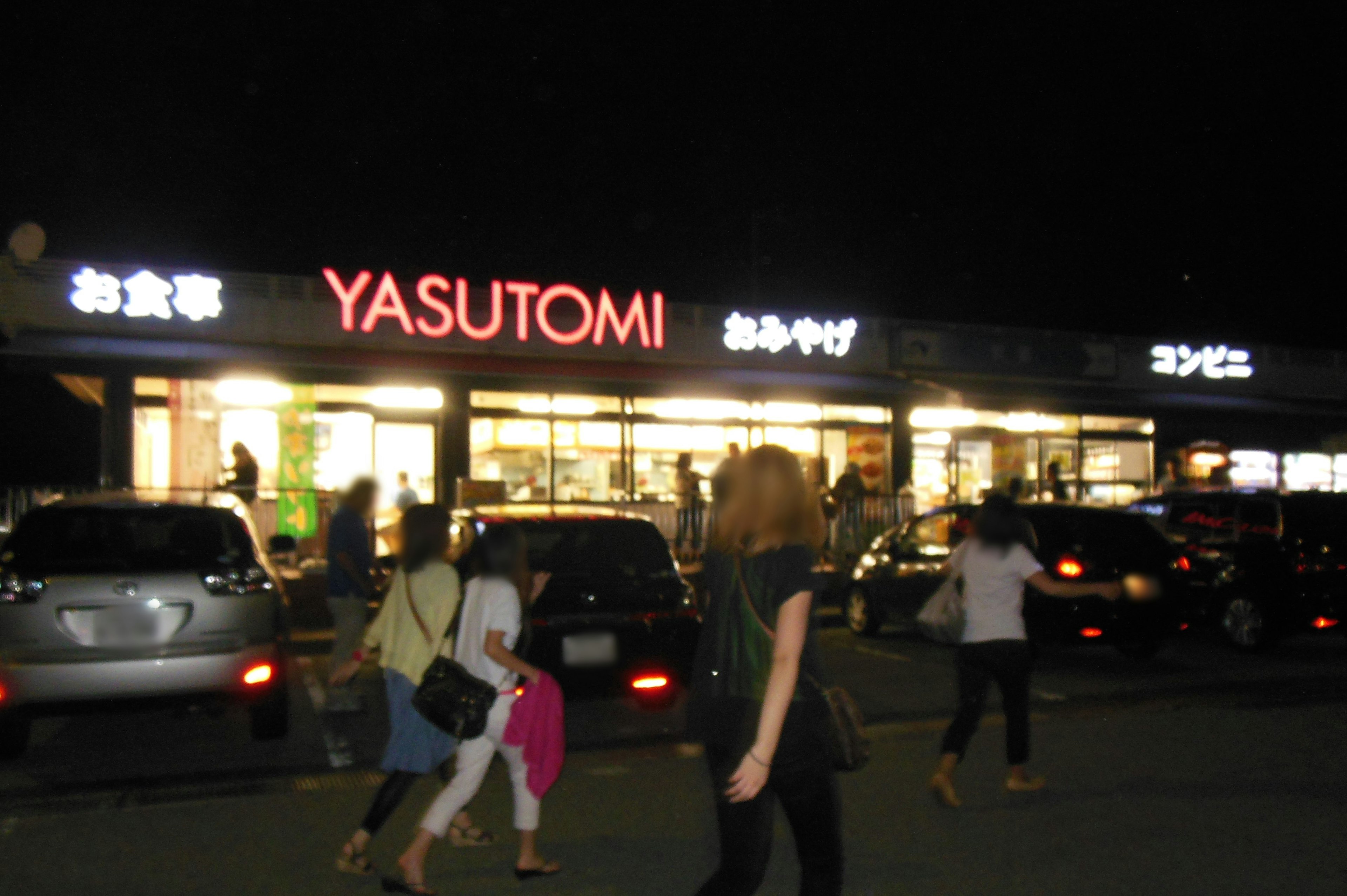 夜のYASUTOMIの店舗前にいる人々と車