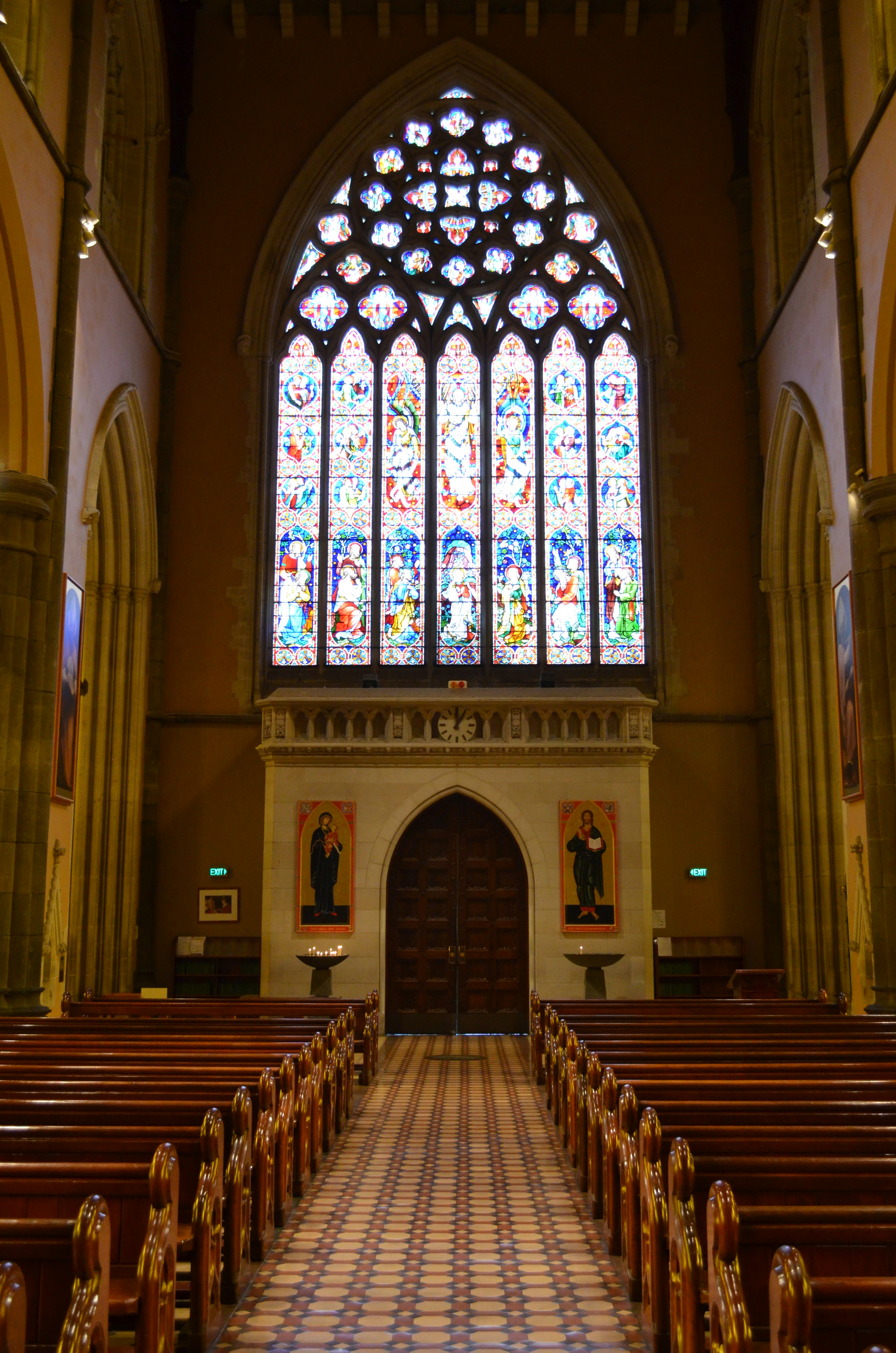 Interior of a church featuring colorful stained glass windows wooden pews and Gothic arches