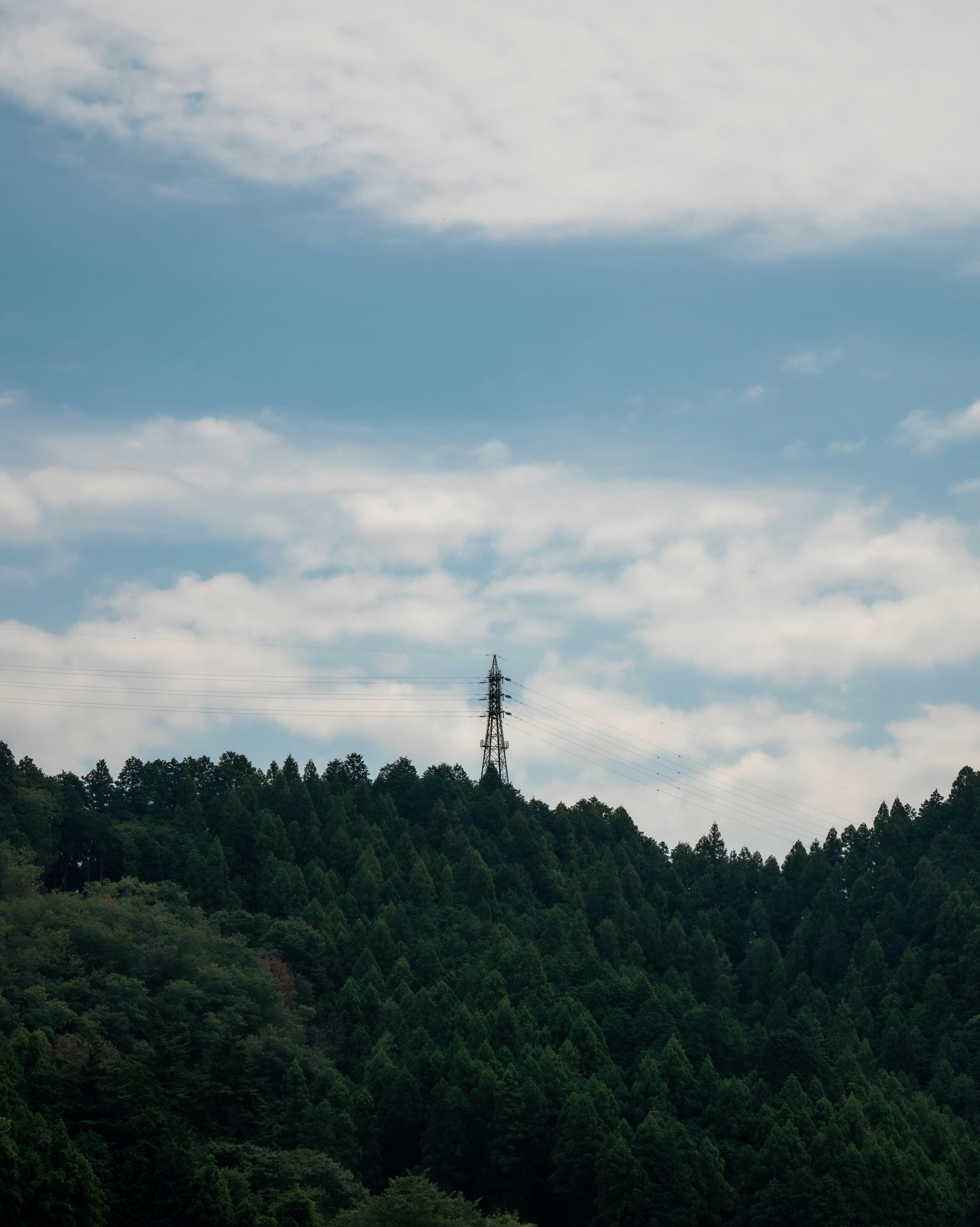 Torre de comunicación en una montaña verde bajo un cielo azul