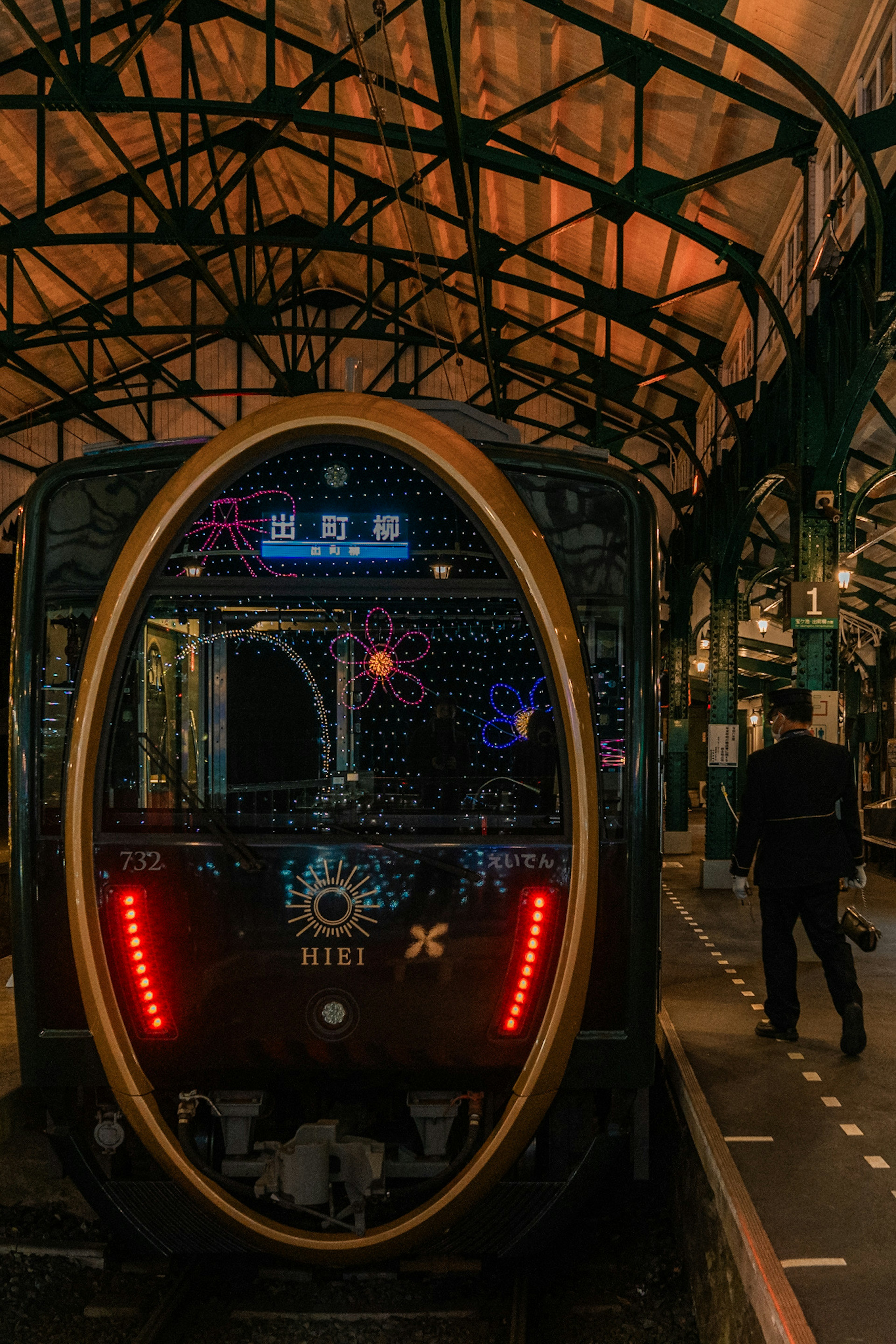 Illuminated train at a station with a person walking