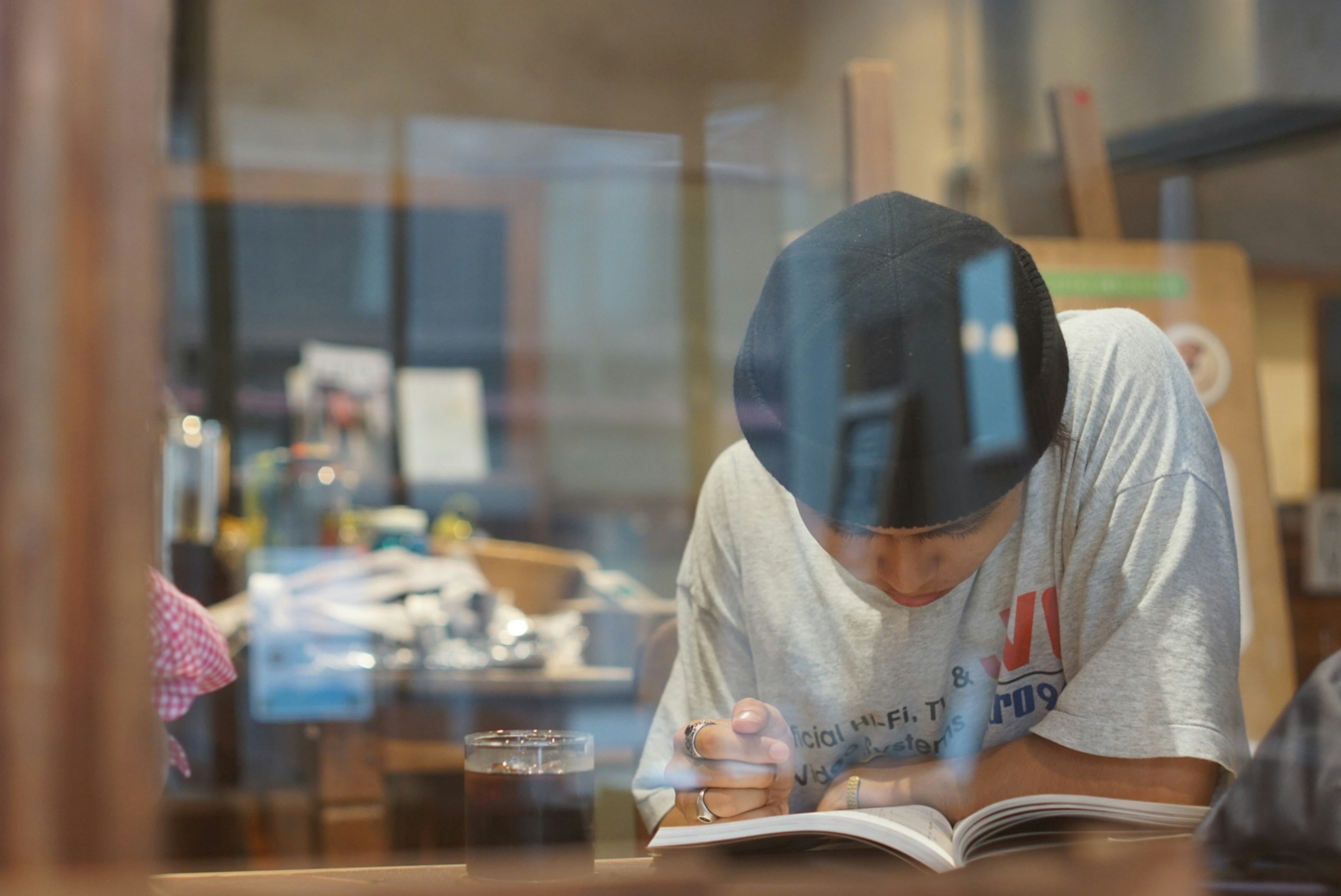 Person reading a book through a window cluttered desk in the background