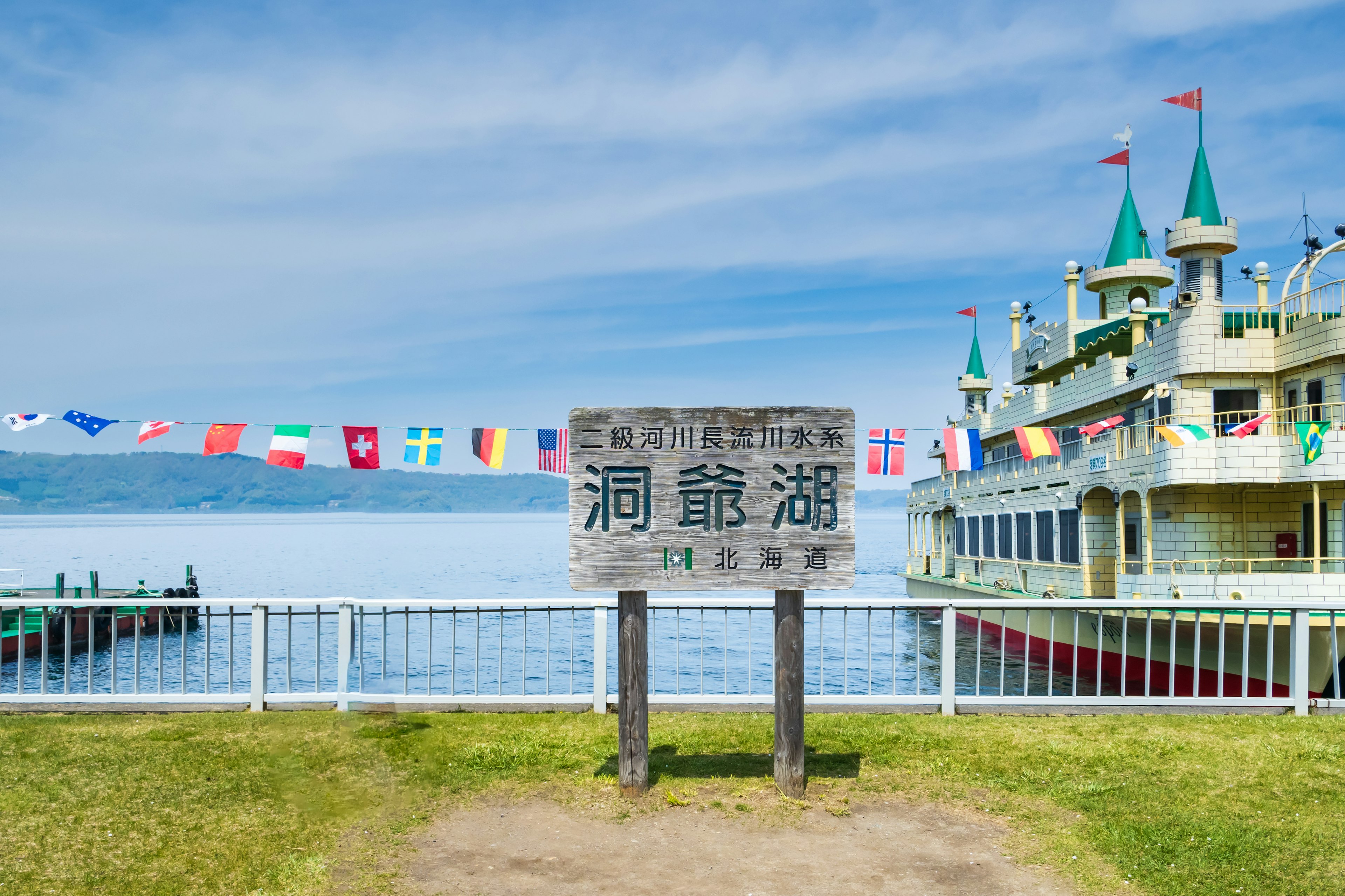 Cartello che indica il nome del lago con bandiere colorate e un edificio unico