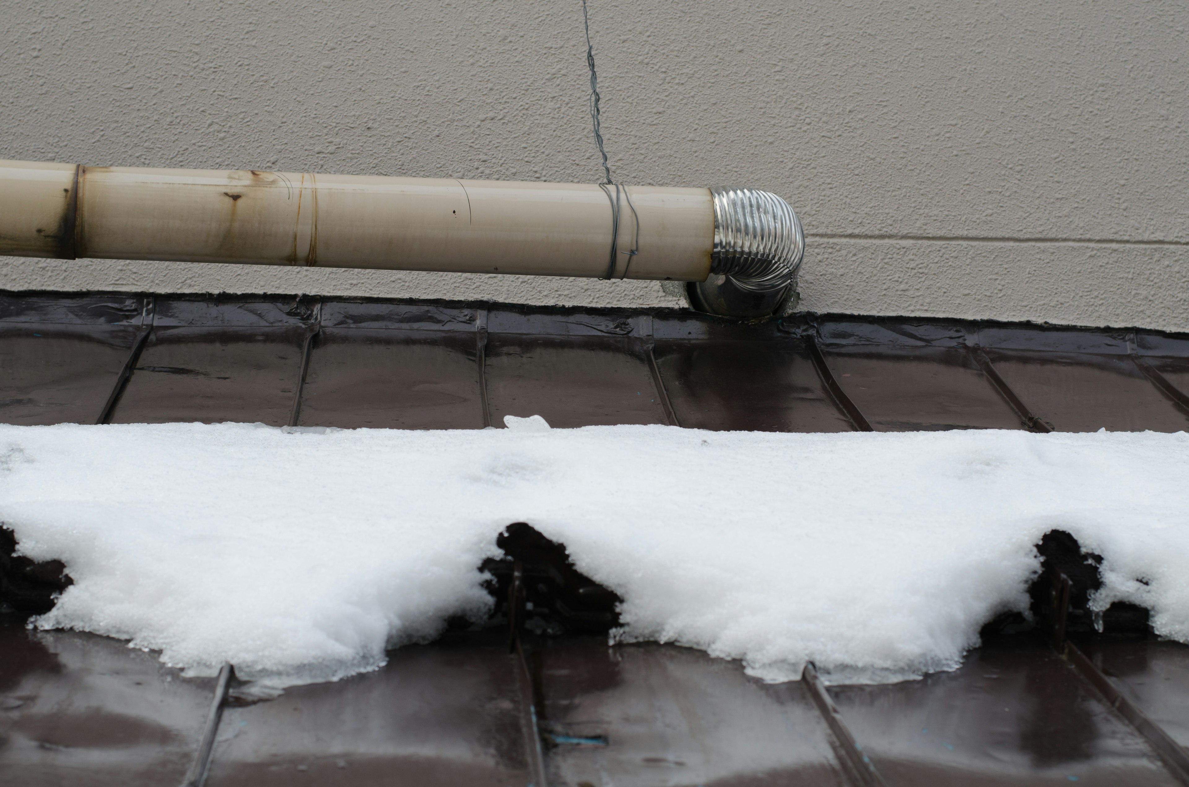 Imagen de un techo con acumulación de nieve y un tubo de drenaje