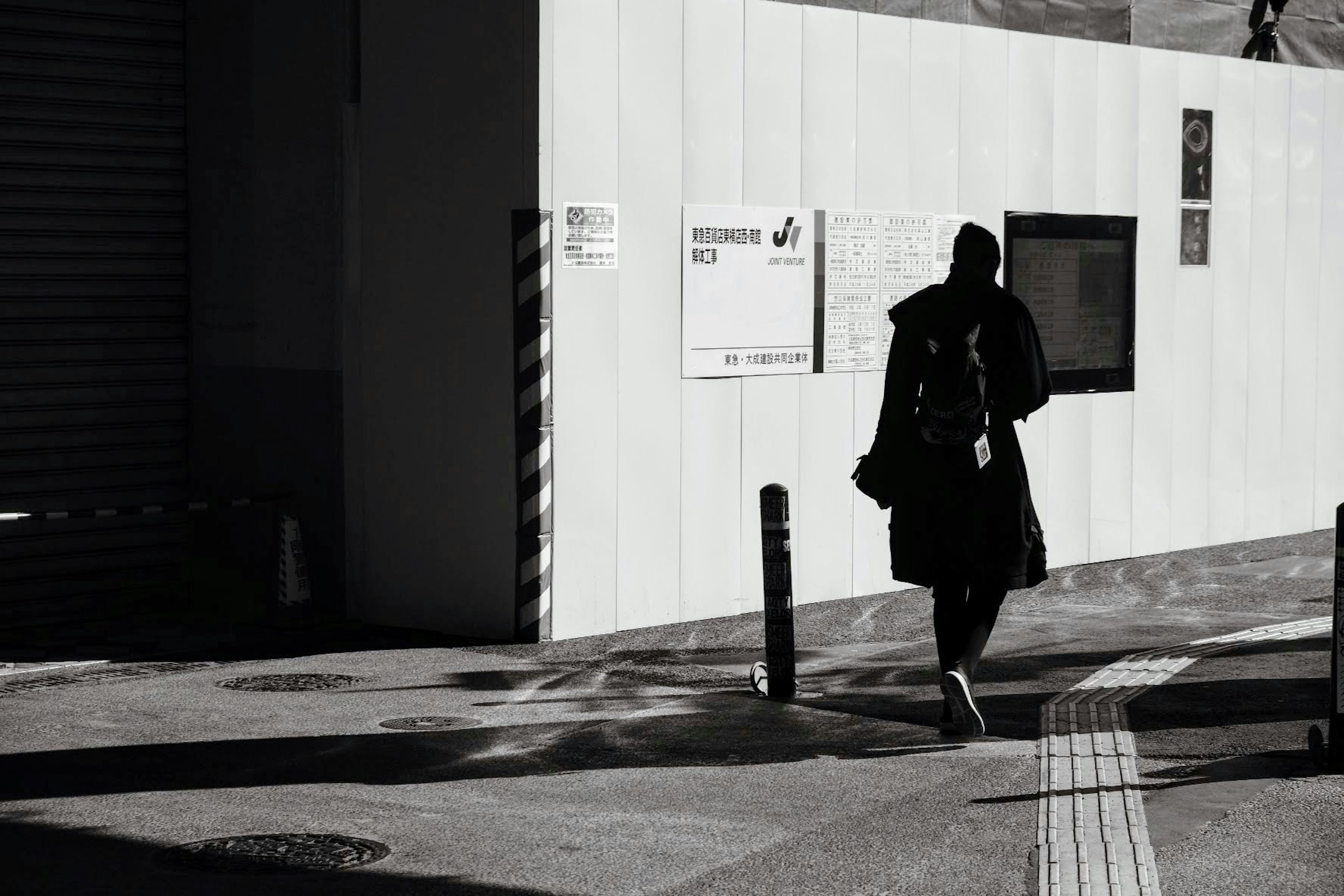 黒いコートを着た人が歩いている都市の風景