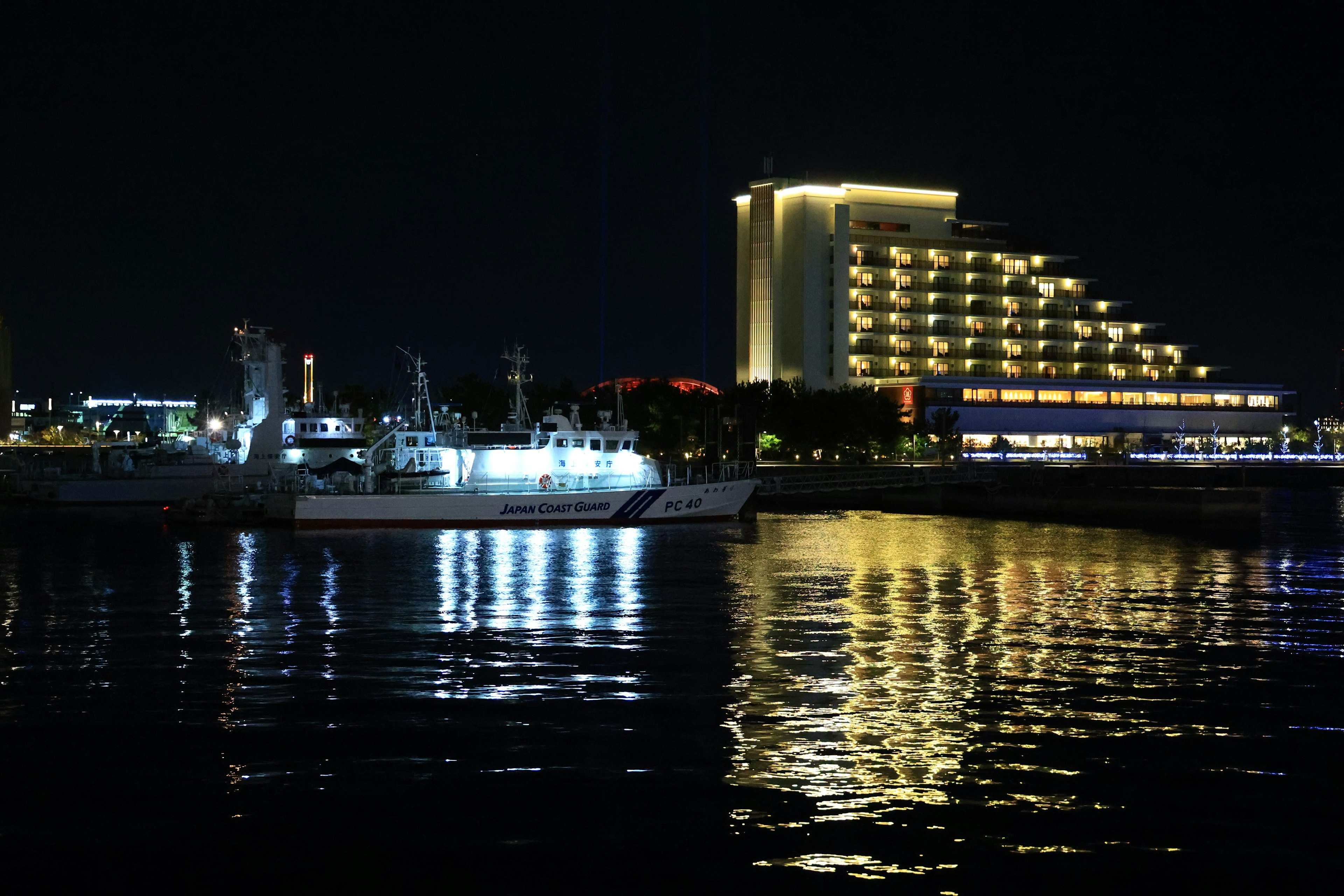 Bellissima vista notturna di un porto con barche illuminate e un hotel